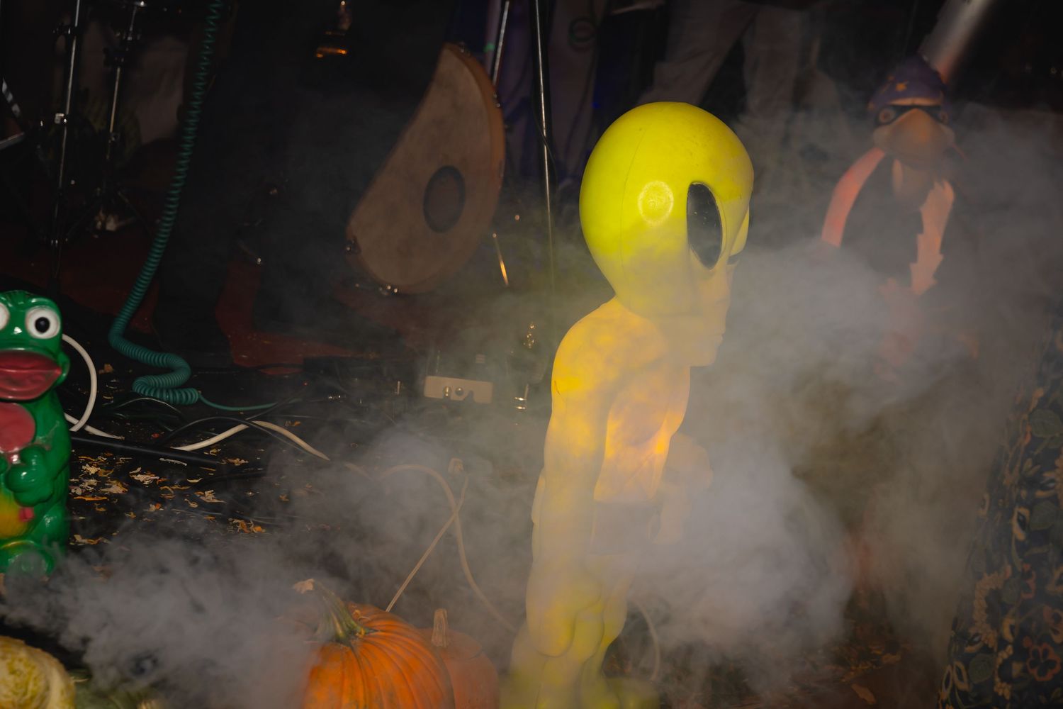 A yellow inflatable decoration stands in misty fog among Halloween decorations at night.
