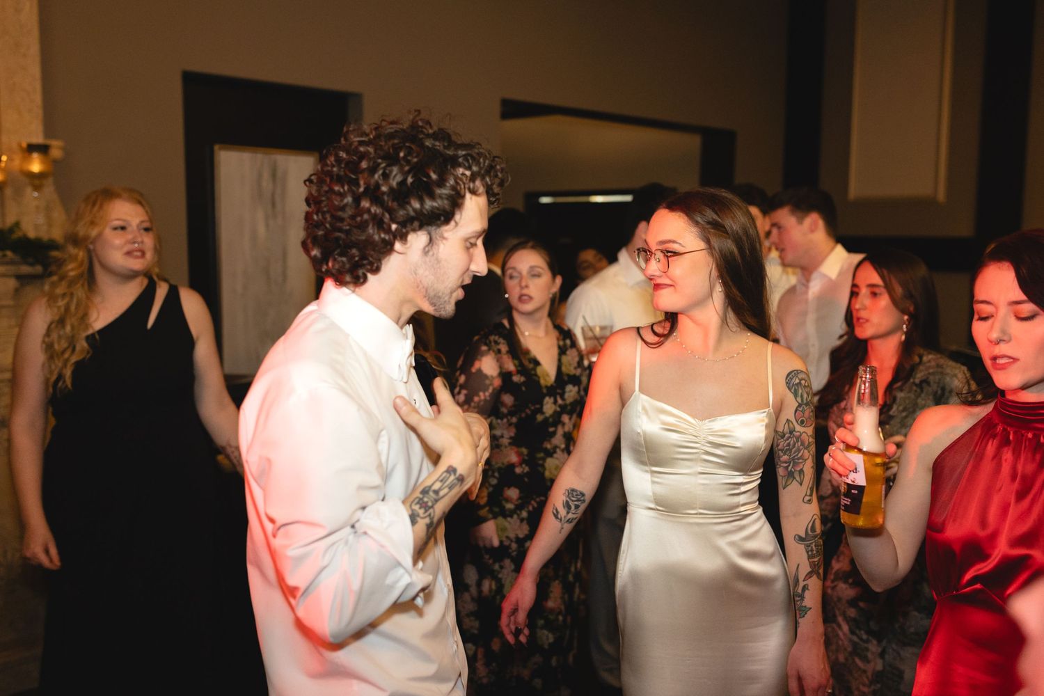 People dancing and celebrating at a wedding reception with someone in a white strapless dress dancing enthusiastically.
