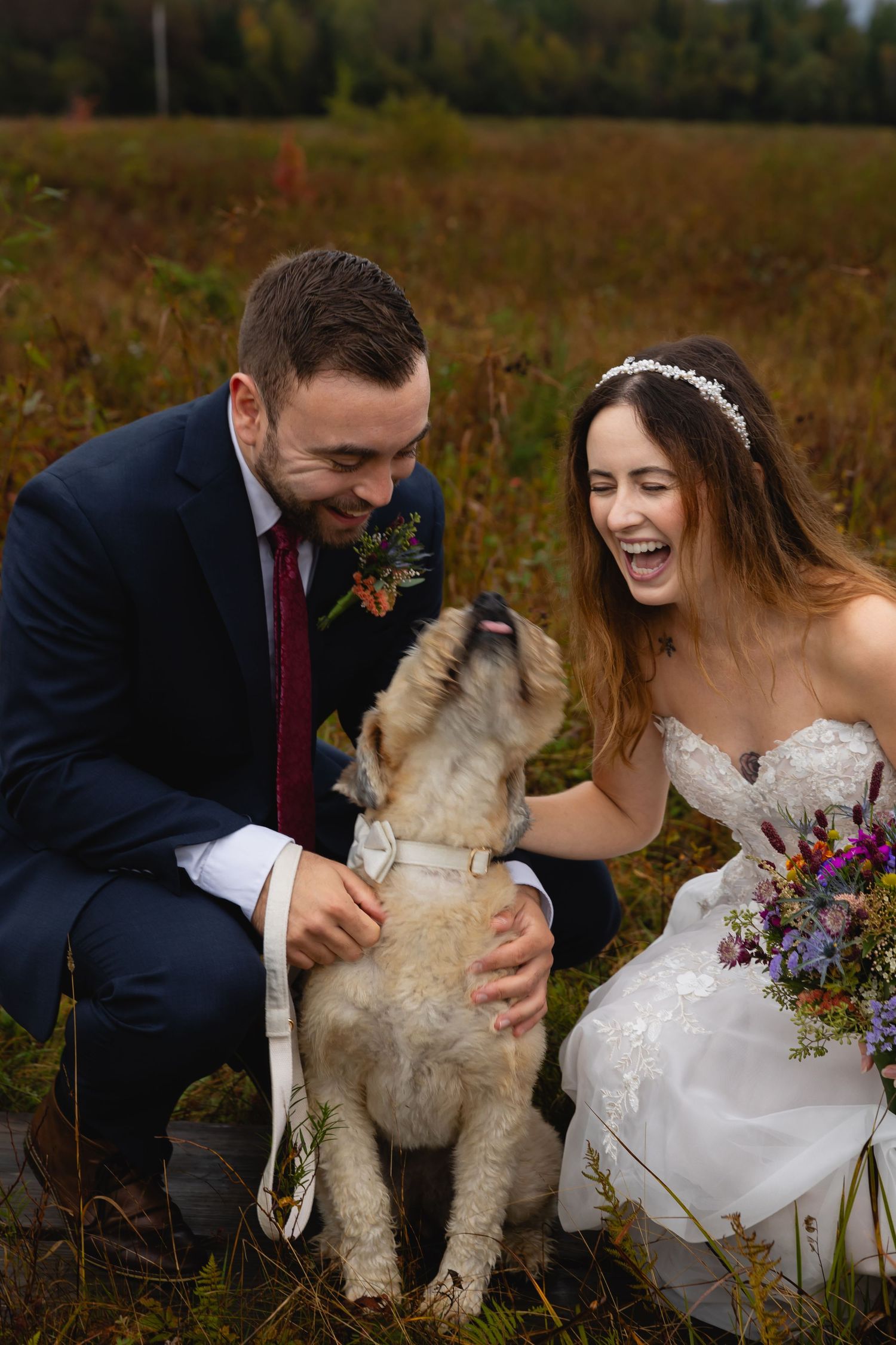 A couple shares laughter with their excited dog during their outdoor mountain wedding.