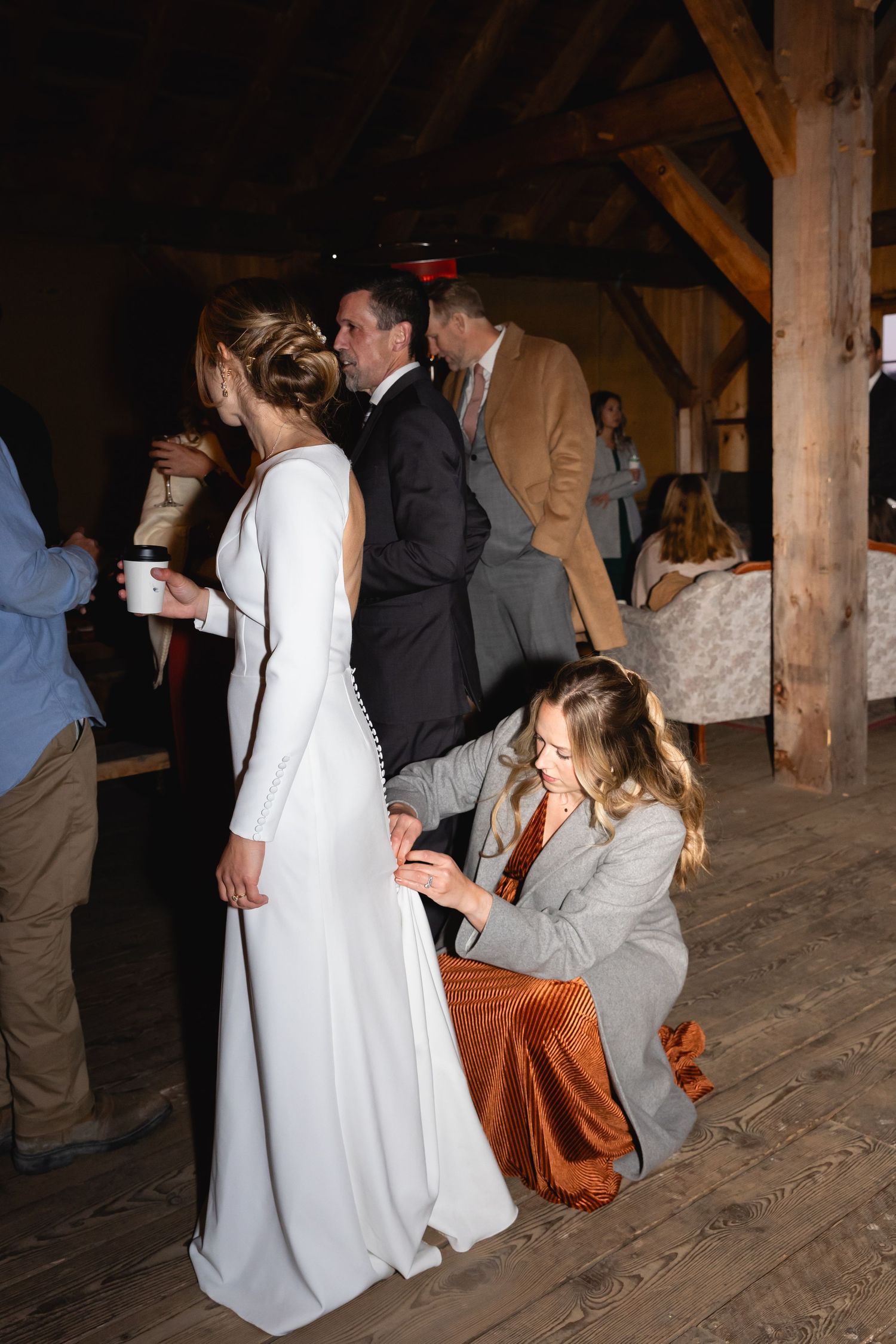 A wedding celebration inside a rustic wooden barn with people gathered in formal attire.