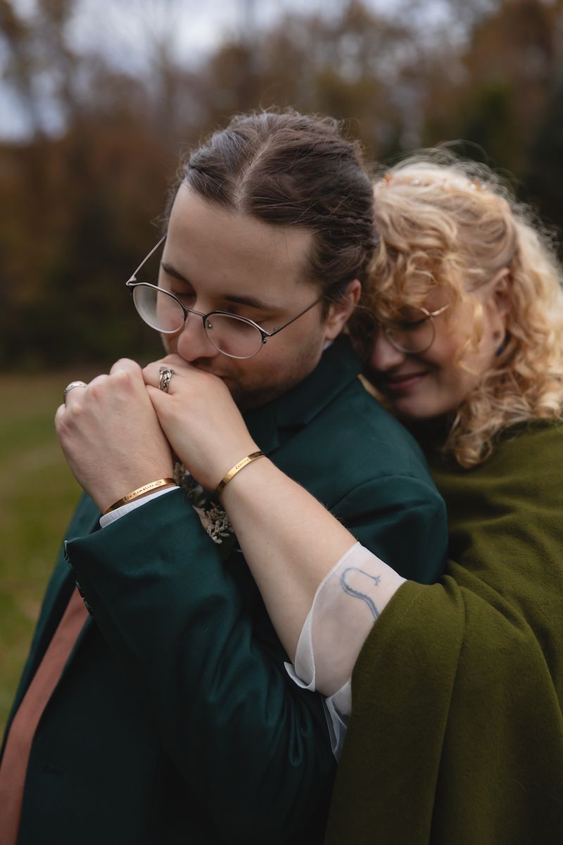 Tender moment shared between couple with emerald jacket and vintage glasses.