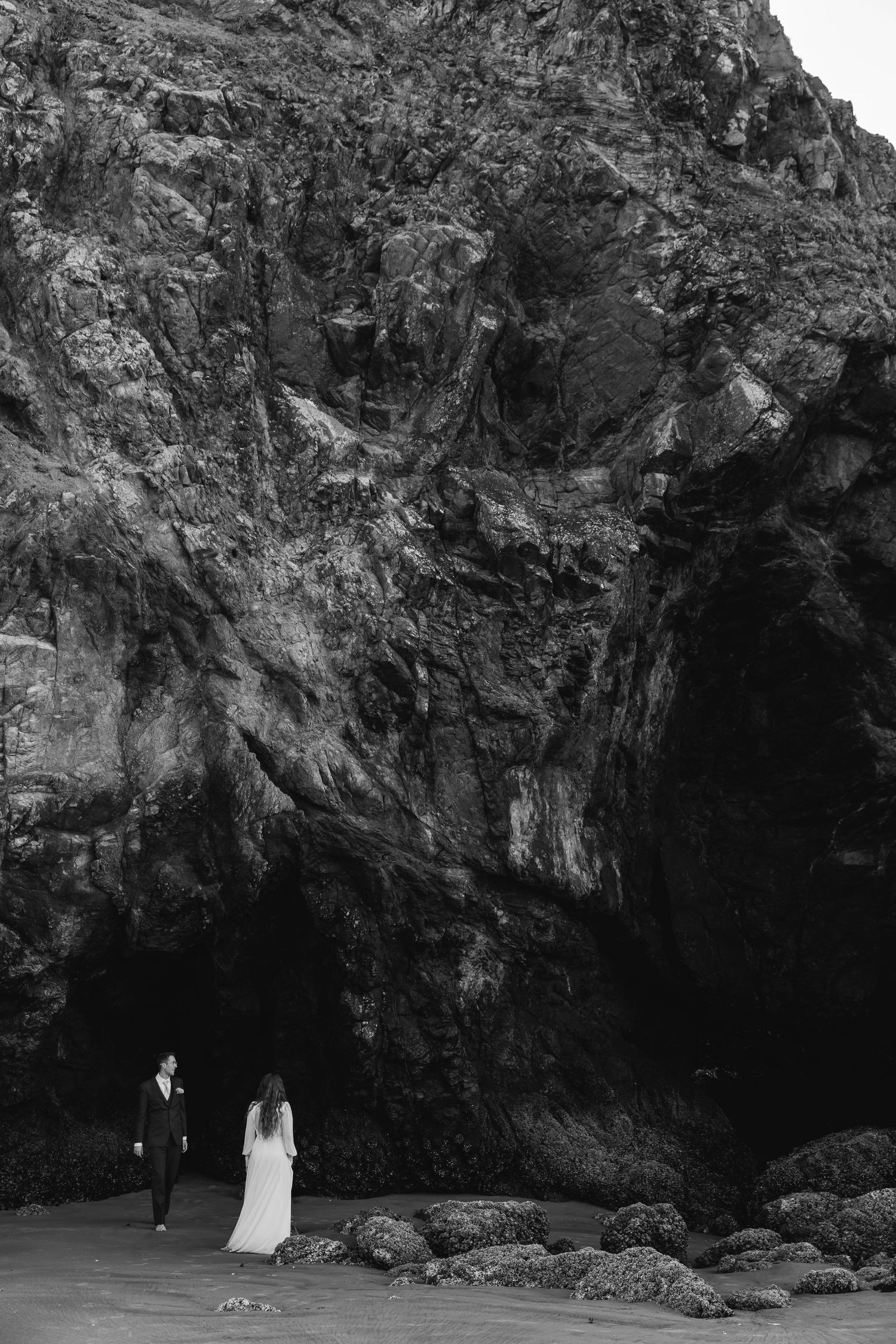 Dramatic black and white photo series showing figures against rugged coastal cave formations at sunset.