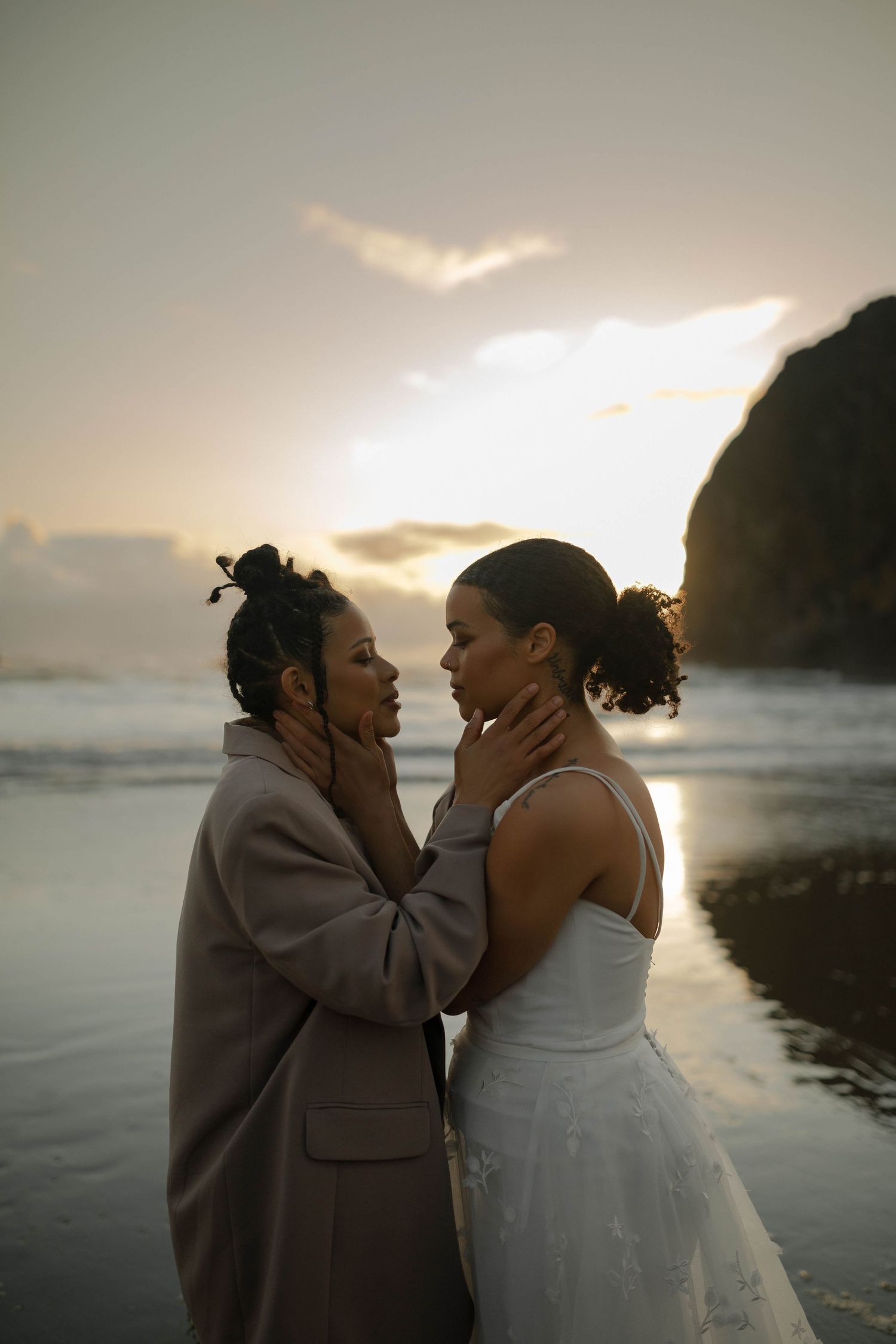 A couple shares a romantic moment during their beach wedding with Haystack Rock at sunset.