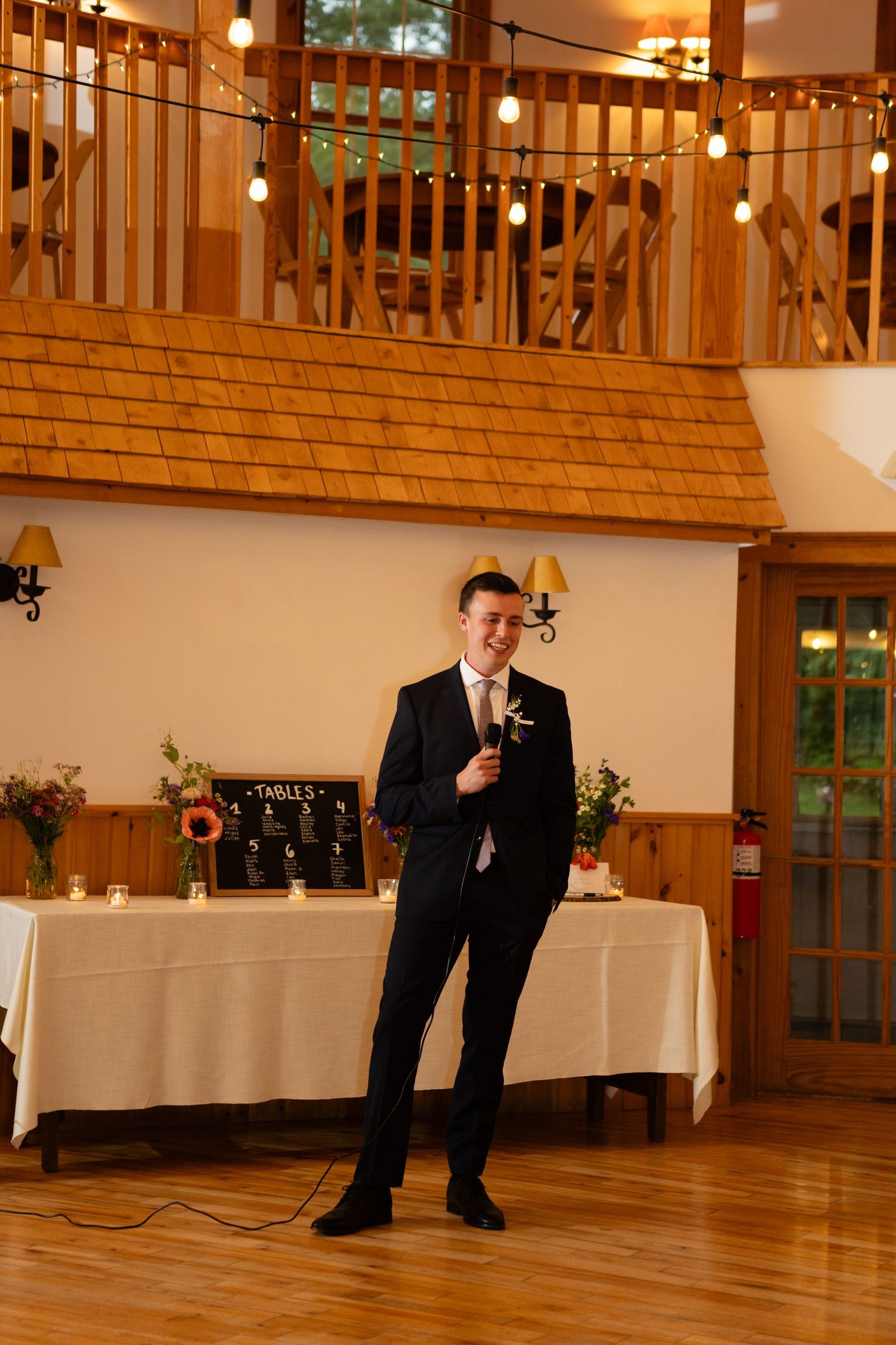 Reception speech in elegant venue with wooden accents and mood lighting.