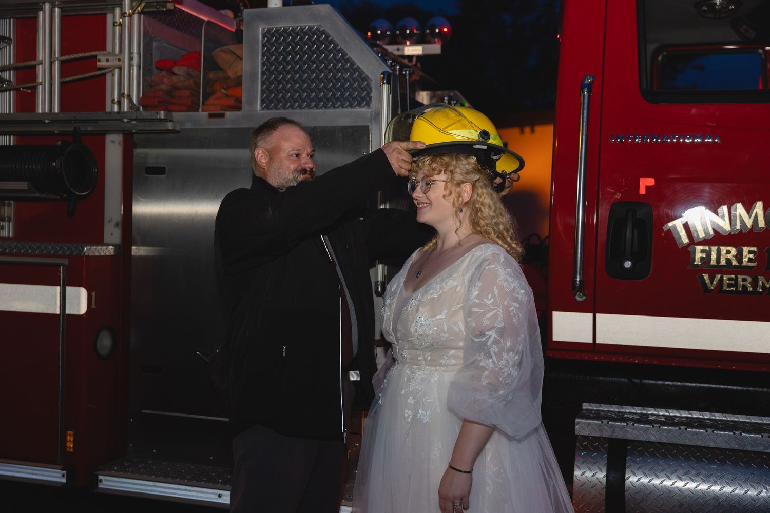 A wedding moment captured in front of a fire truck at night.