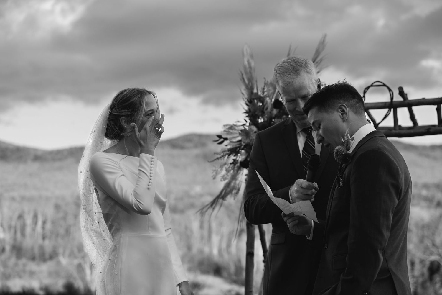 Black and white photo of an outdoor wedding ceremony in a mountainous landscape.