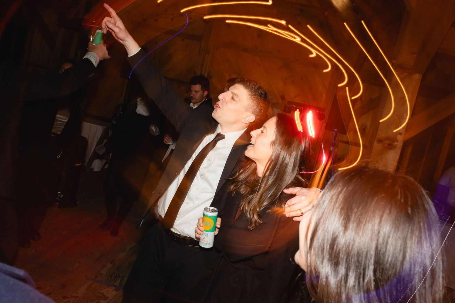 Party scene at night with long exposure light trails and someone dancing with a drink bottle in hand.