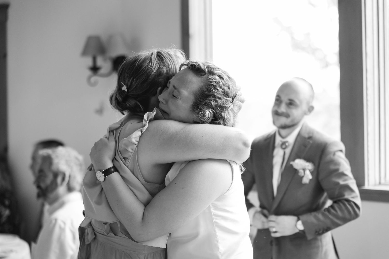 A couple shares a romantic kiss during their wedding celebration while guests look on in the background.