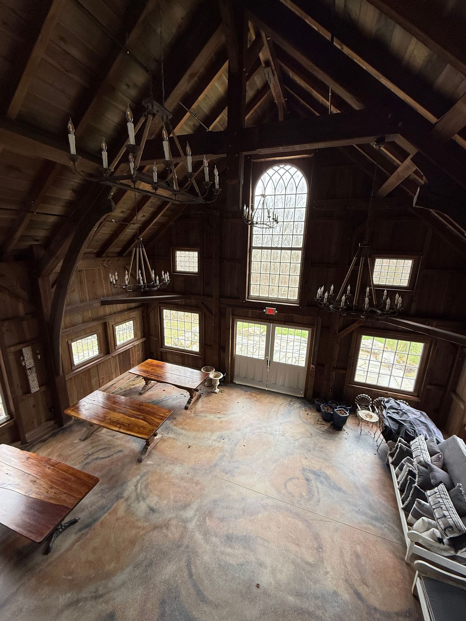 Interior view of a rustic wooden church or meeting hall with arched windows, exposed beams, and high vaulted ceiling.