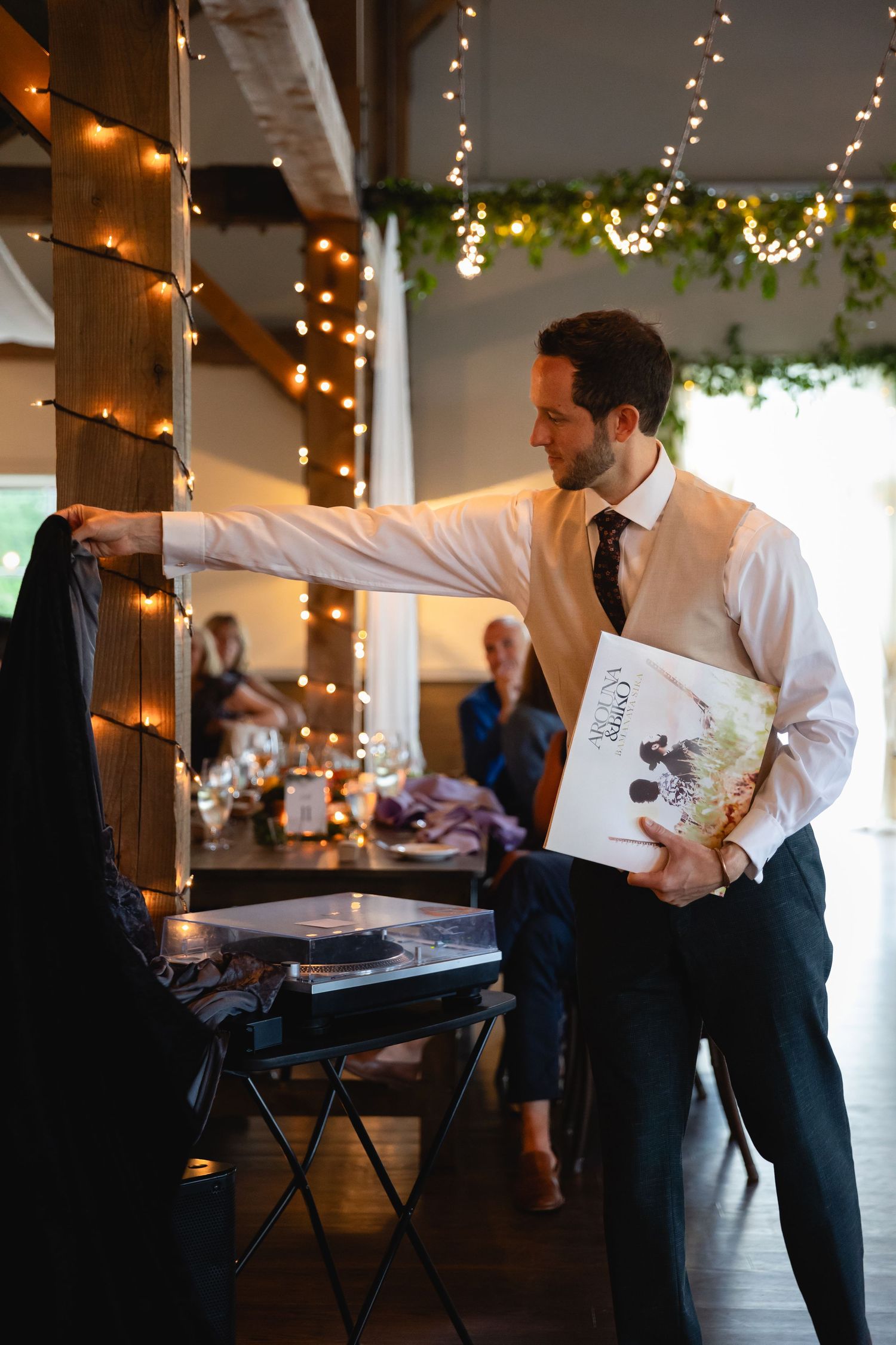 DJ setting up vinyl records and sound equipment at an indoor event.