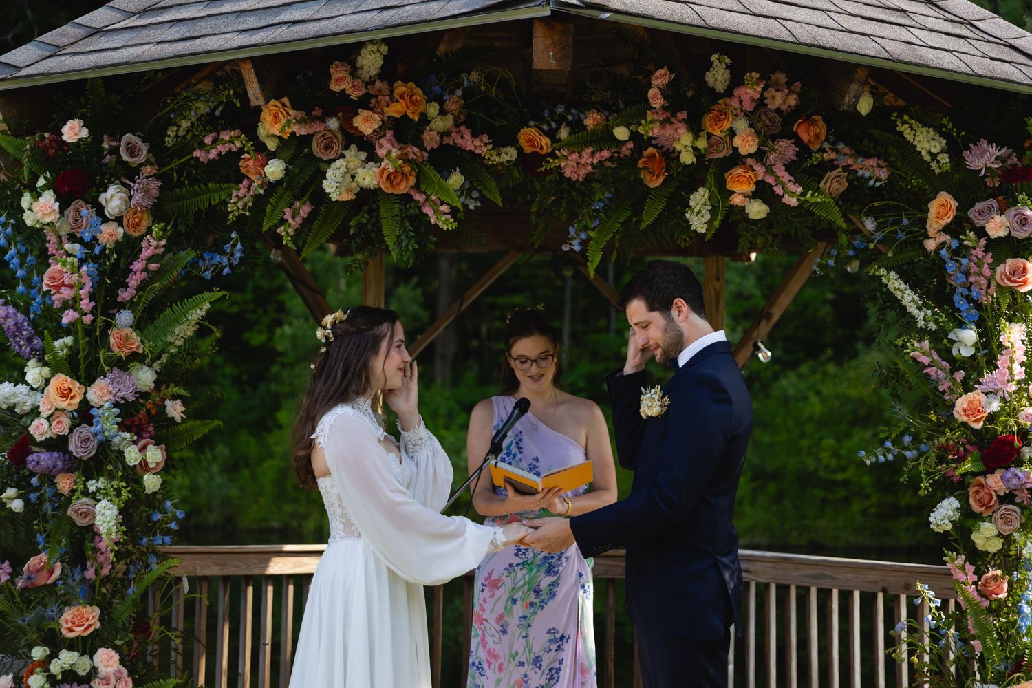 Wedding party stands under floral arch during outdoor garden ceremony celebration.