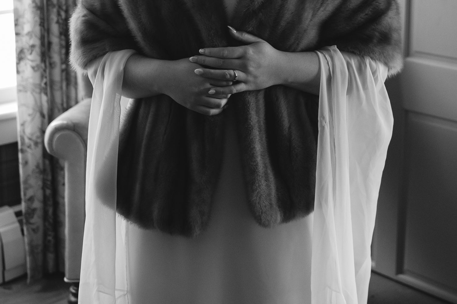 Elegant black and white photo of hands crossed over a formal dress.
