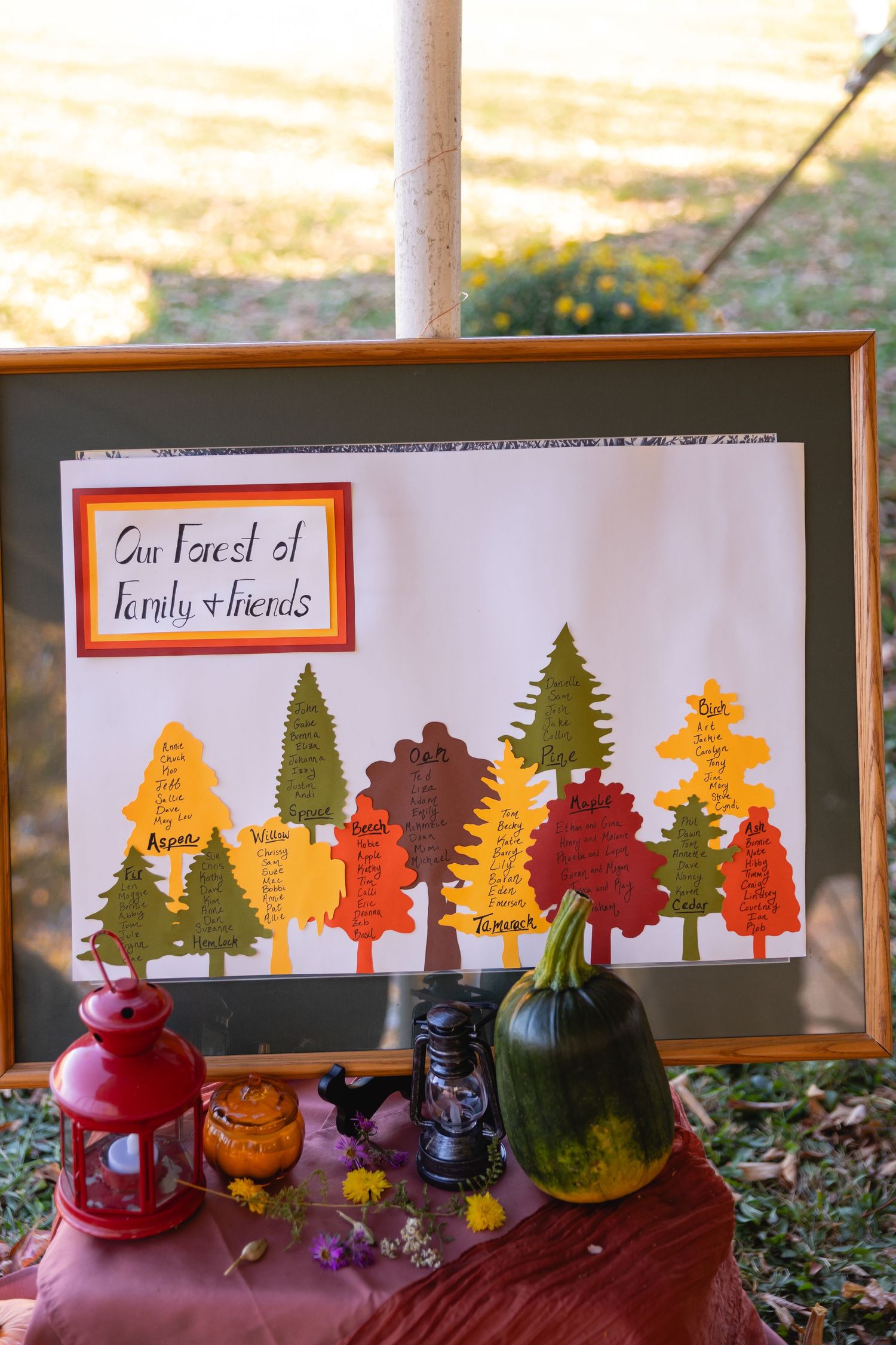 Three framed artworks display colorful paper cutout forest scenes with autumn trees in orange, red, and green.