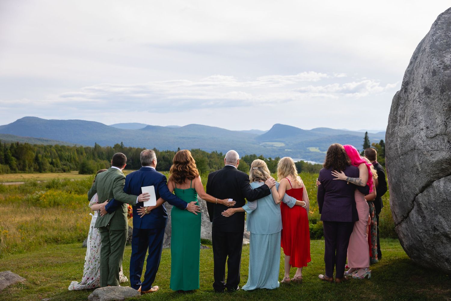 A panoramic sequence shows a group of people standing between large stone monoliths at a scenic outdoor location.