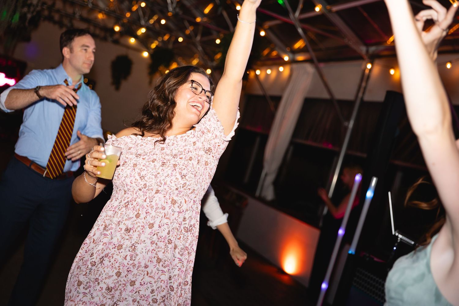 People dancing together at a dimly lit party venue with colorful lighting and festive atmosphere.
