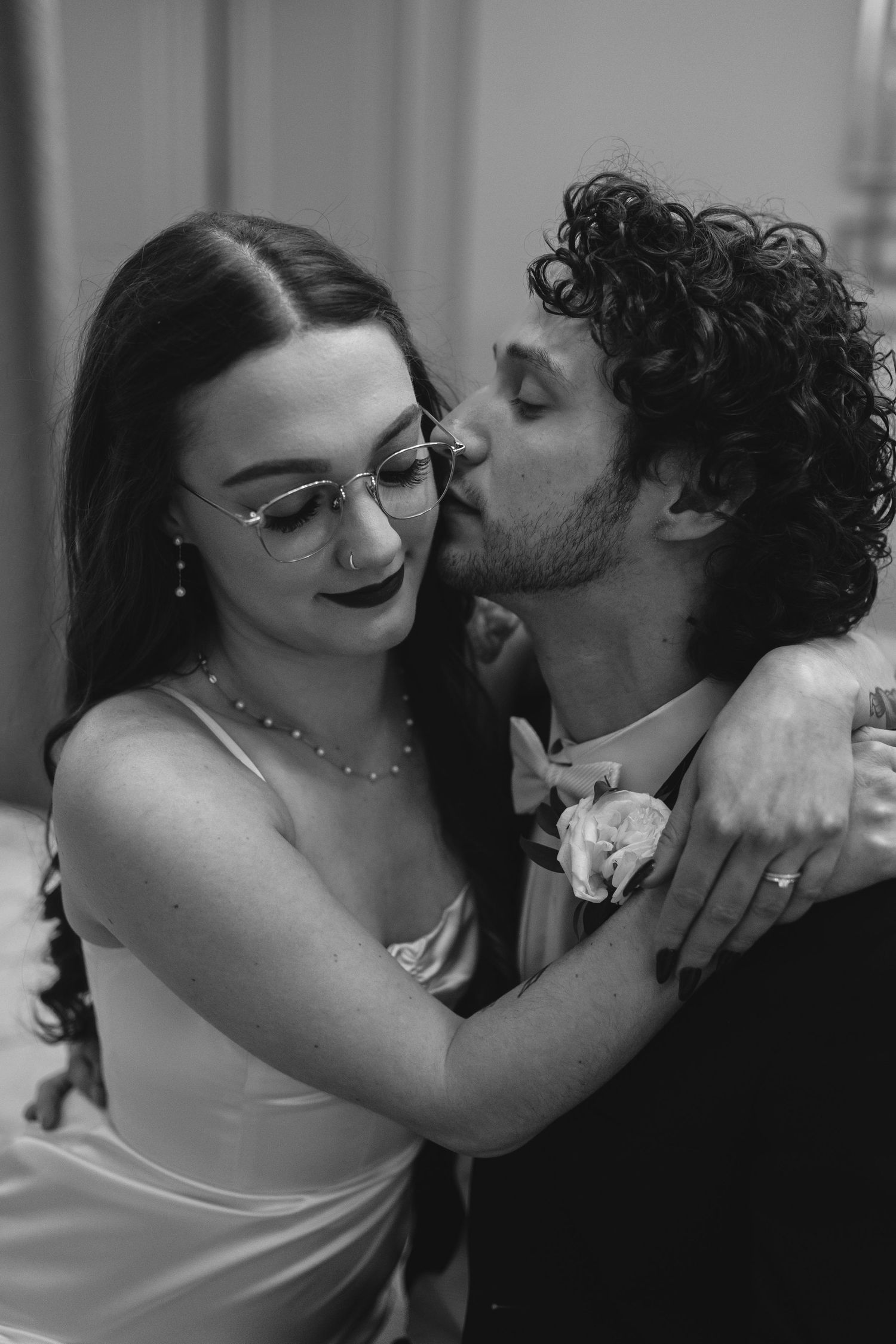 A romantic black and white wedding portrait showing an intimate moment between a couple in formal attire.