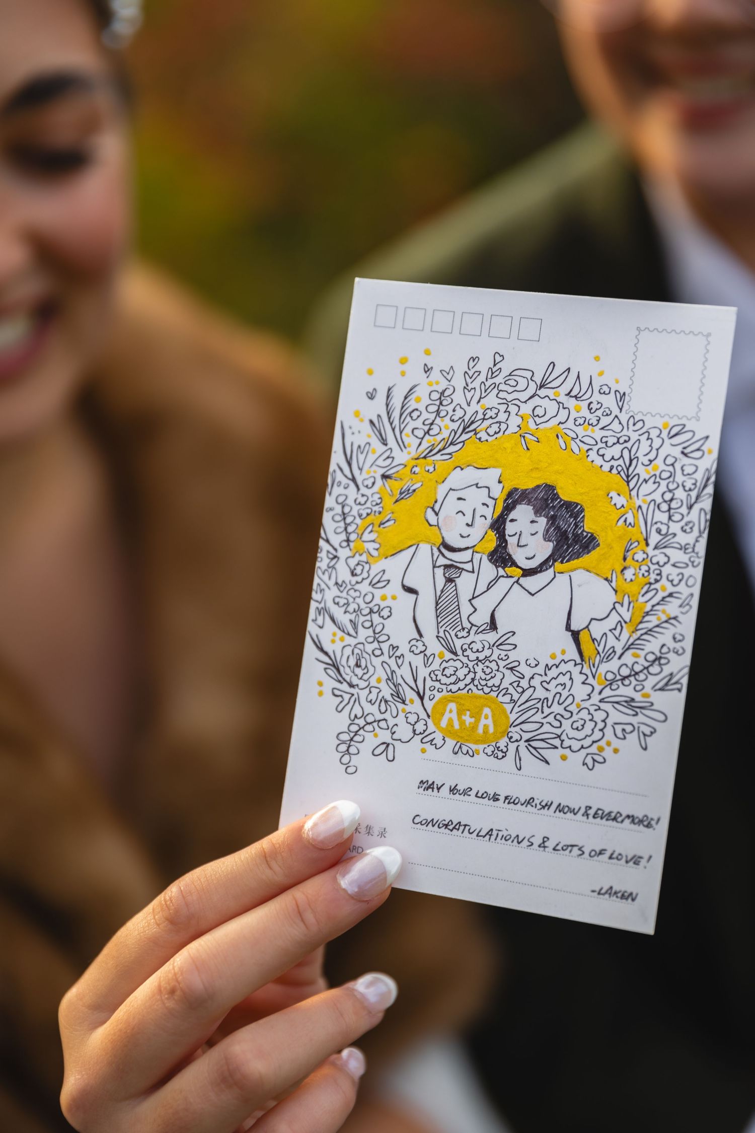Hand holding a custom illustrated wedding invitation with yellow and floral design elements.