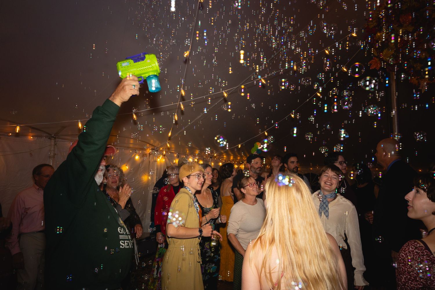 People dance and celebrate at a nighttime party with sparkling confetti falling from above.