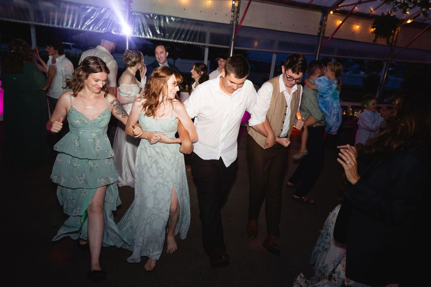 People dancing and celebrating on a dark dance floor at a festive event with atmospheric lighting.