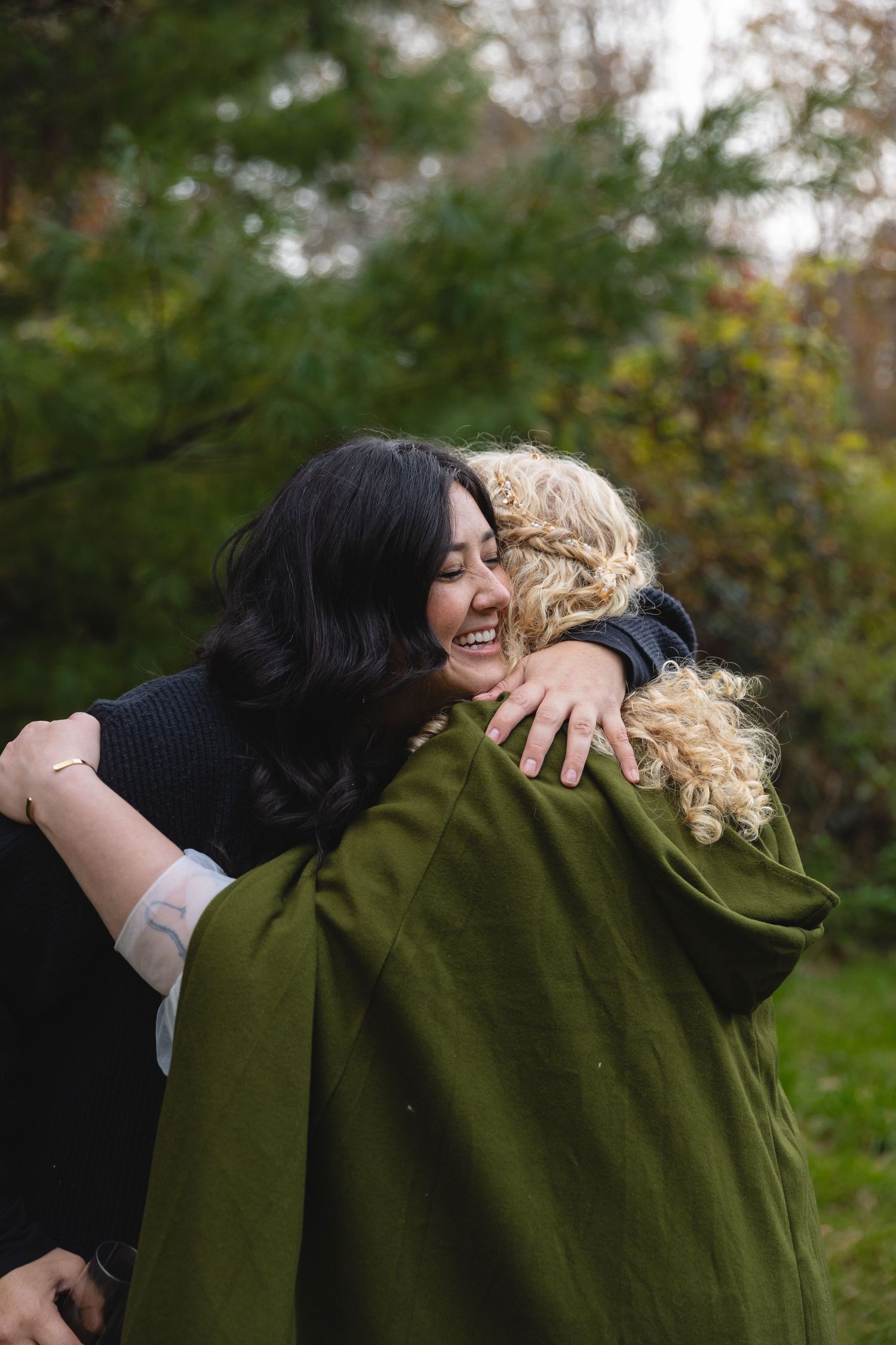 Two wedding guests sharing an emotional embrace outdoors.