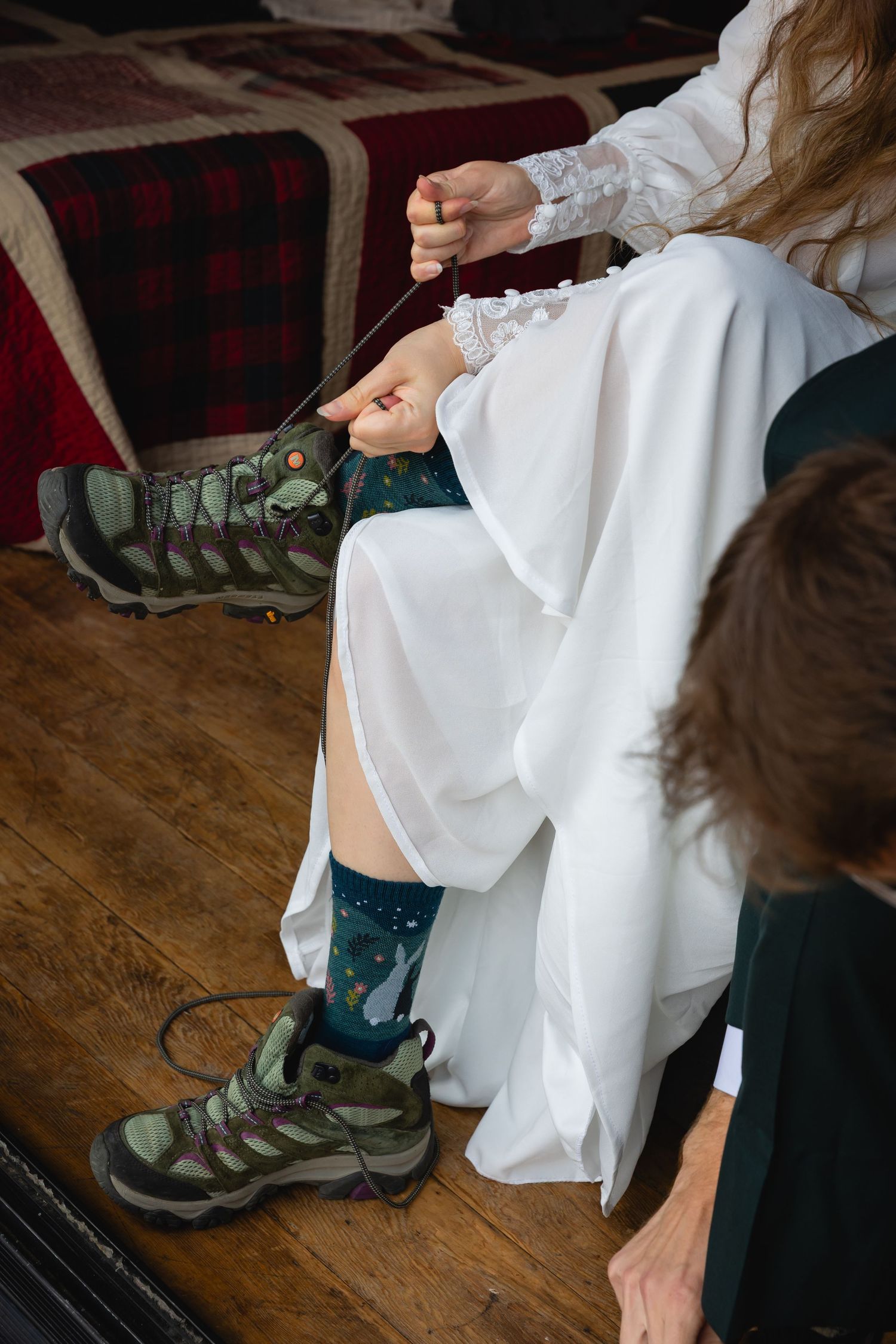 A person wearing hiking boots sits on a wooden floor while putting on white socks in a series of sequential photos.
