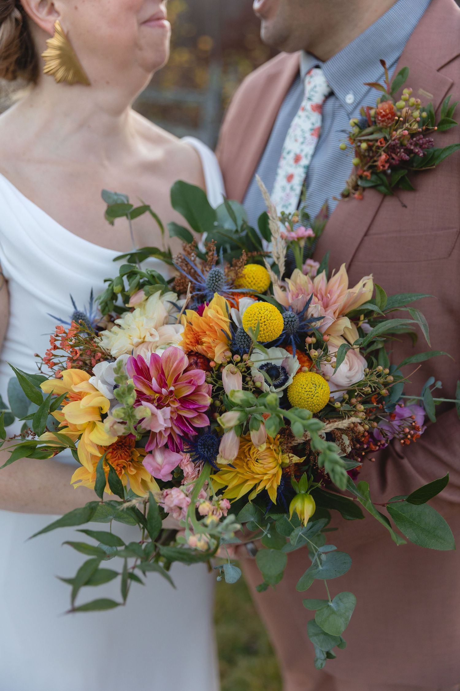 Colorful wedding bouquet features sunflowers, dahlias, and mixed wildflowers.