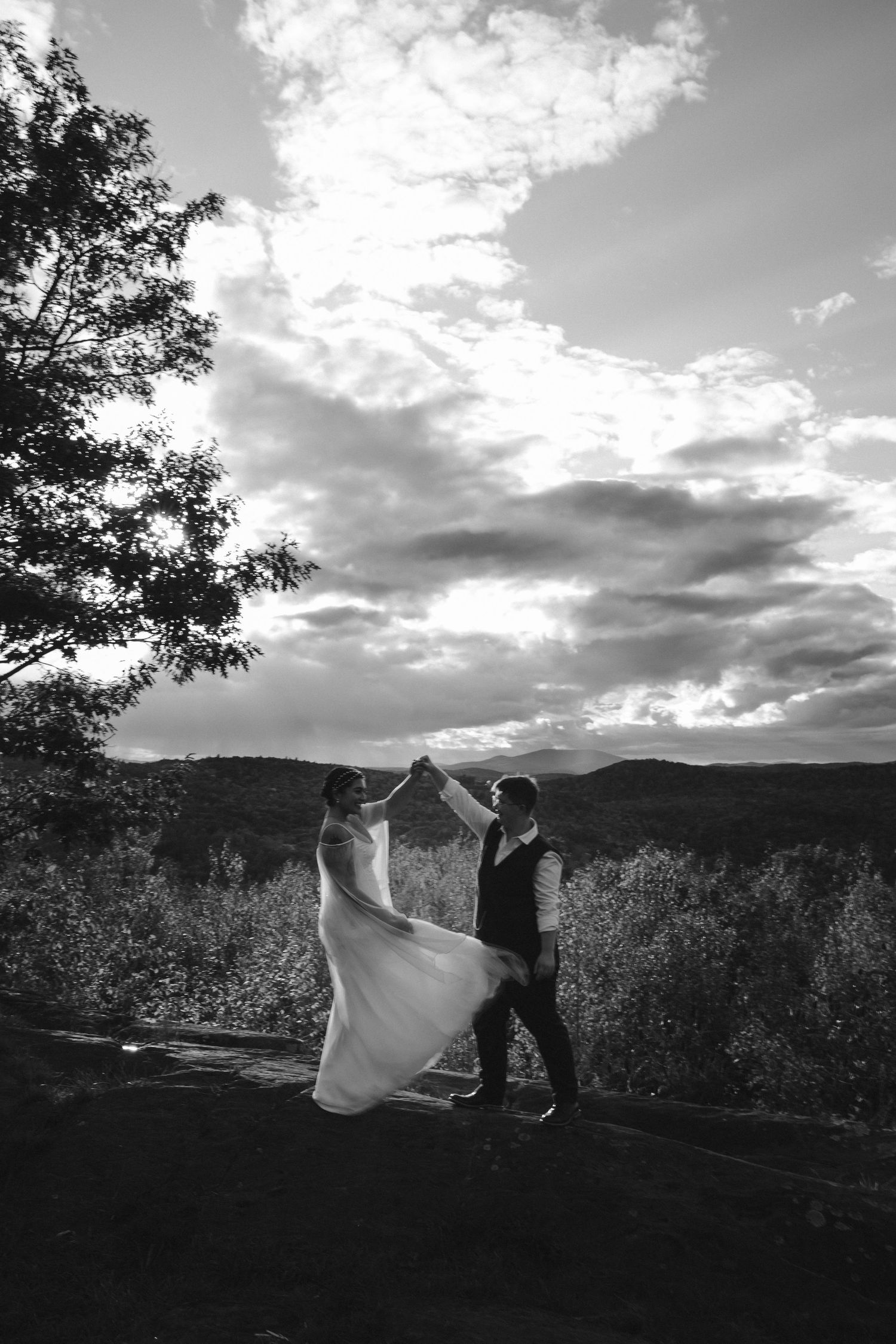 A dramatic black and white silhouette of a couple dancing against a cloudy mountain backdrop.