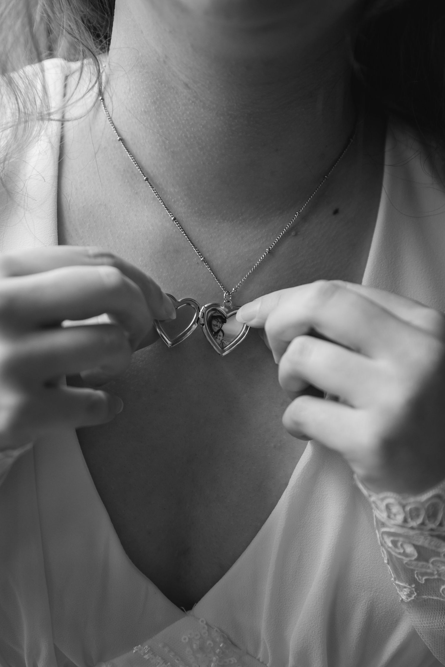 A series of black and white close-up photos showing a delicate V-shaped necklace against bare skin.