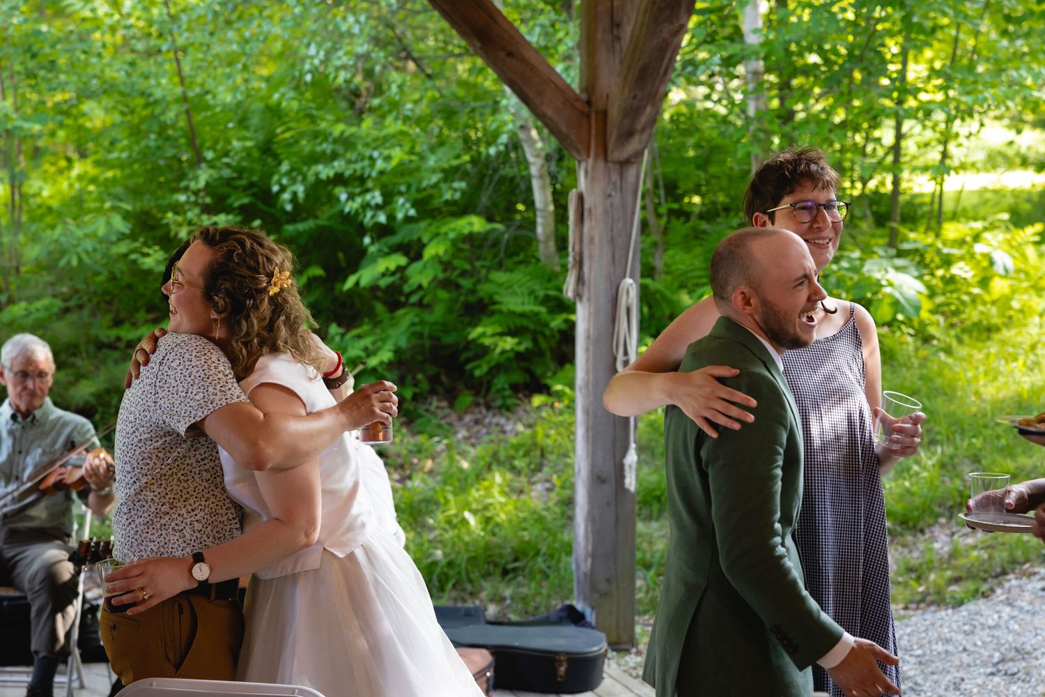 A couple shares a romantic dance moment in a lush green garden setting during an outdoor celebration.