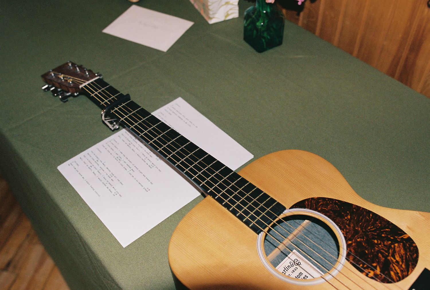 A guitar neck with frets and strings shown in a sequence of close-up shots on a green surface.