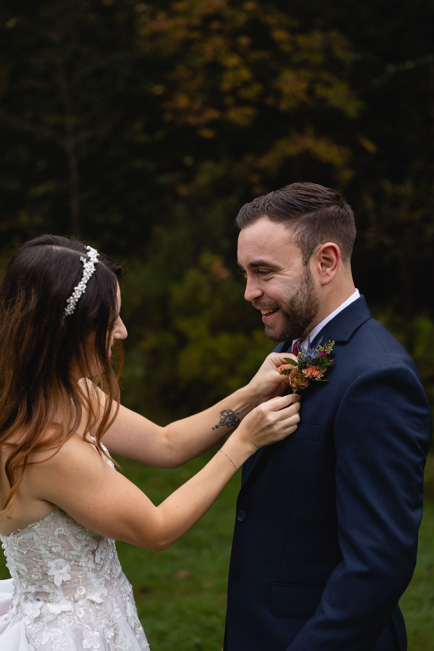 A wedding couple shares an intimate moment while adjusting a boutonniere.