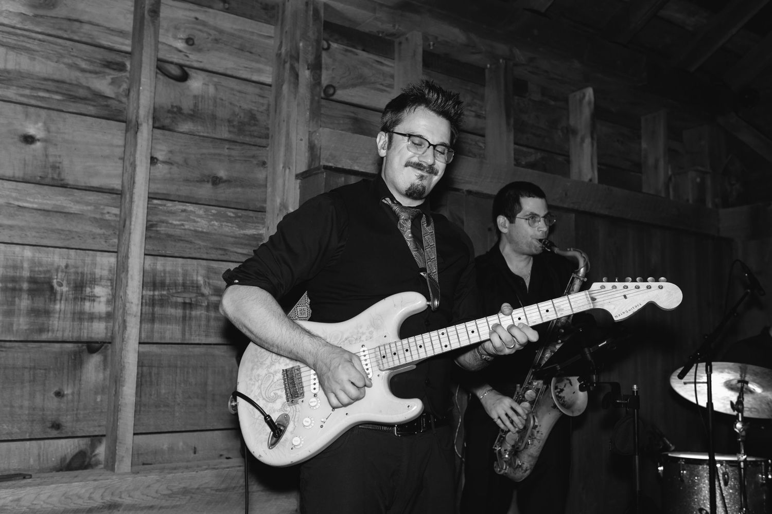 Musician plays electric guitar in a dimly lit wooden venue during a performance.