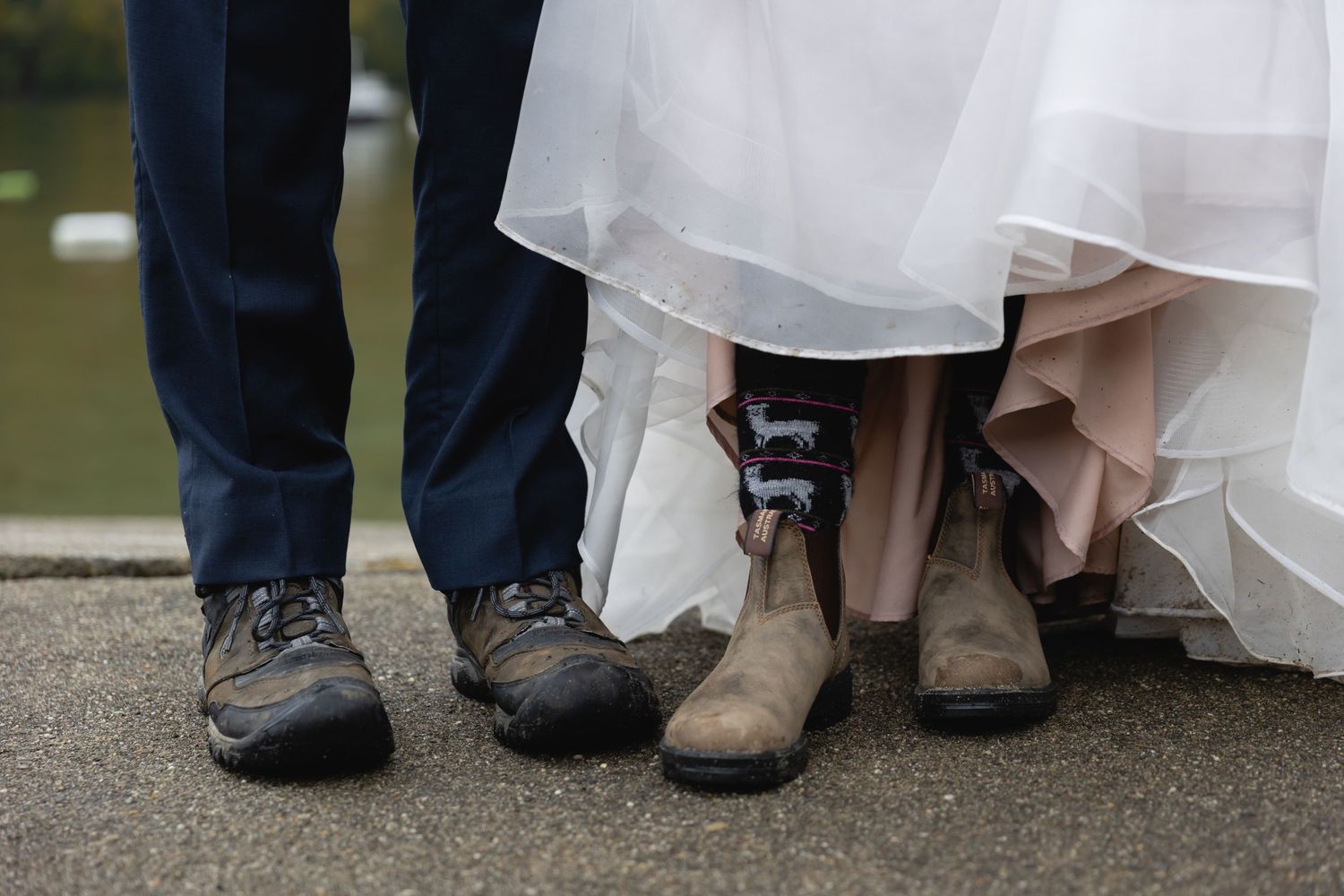 Wedding couple wearing hiking boots under formal attire standing on pavement.