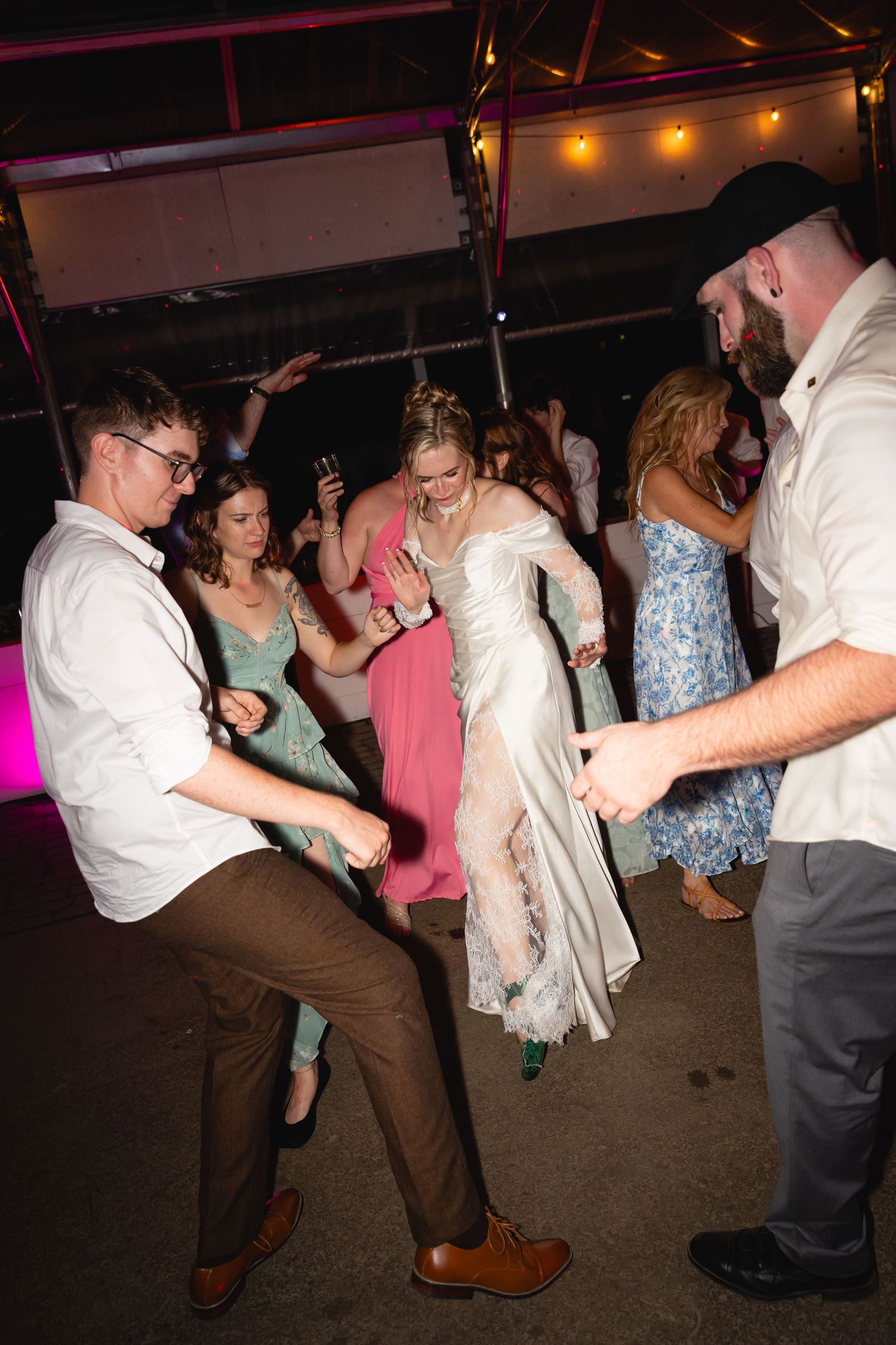 People dancing energetically at a party with colorful lighting and festive atmosphere.