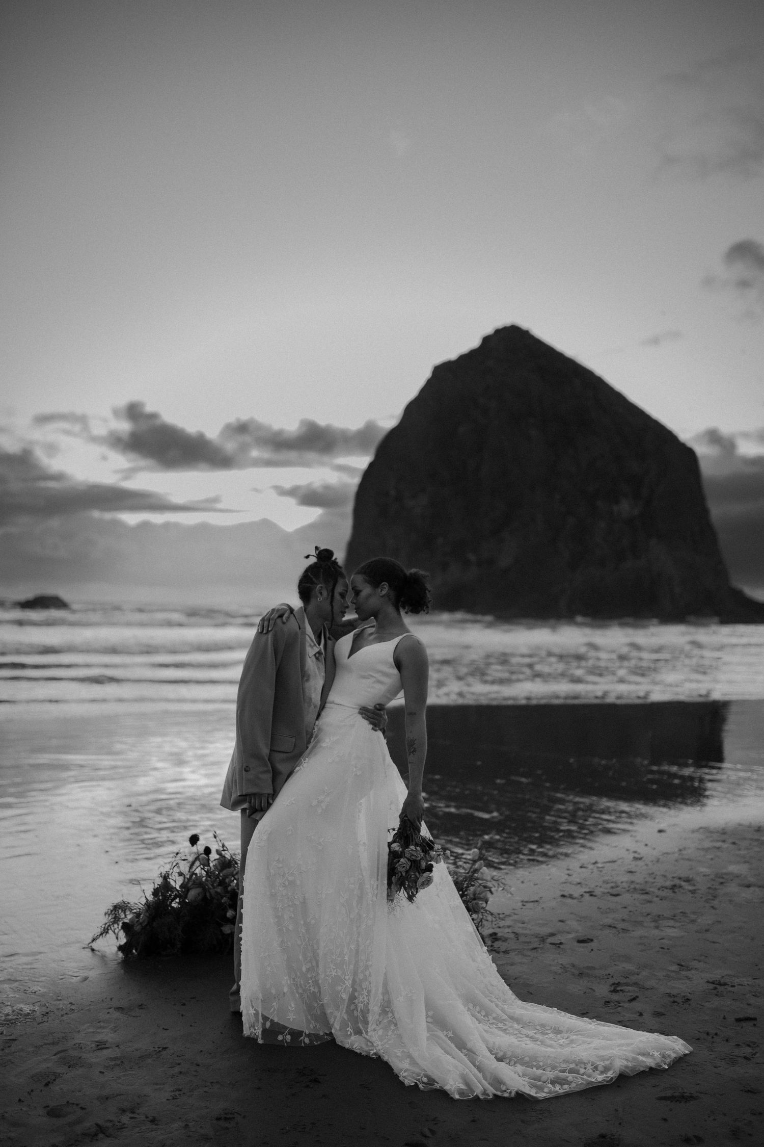 A black and white wedding portrait captured on the shores of Cannon Beach at sunset.