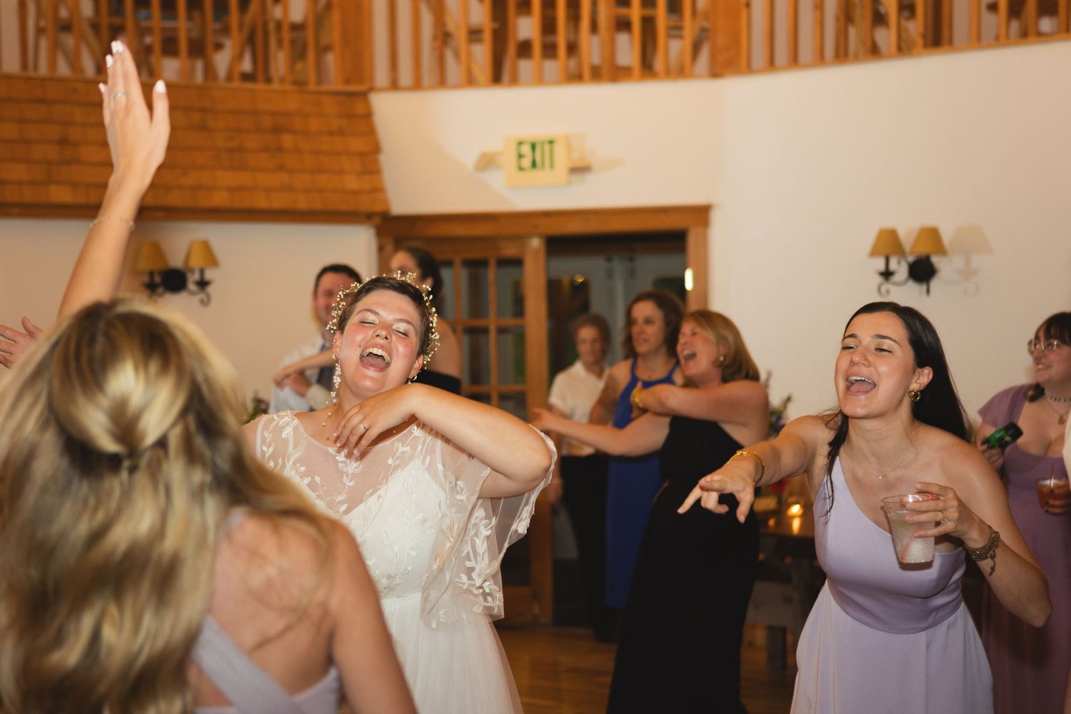 Celebratory dancing at a wedding reception with attendees in formal attire and purple bridesmaid dresses.