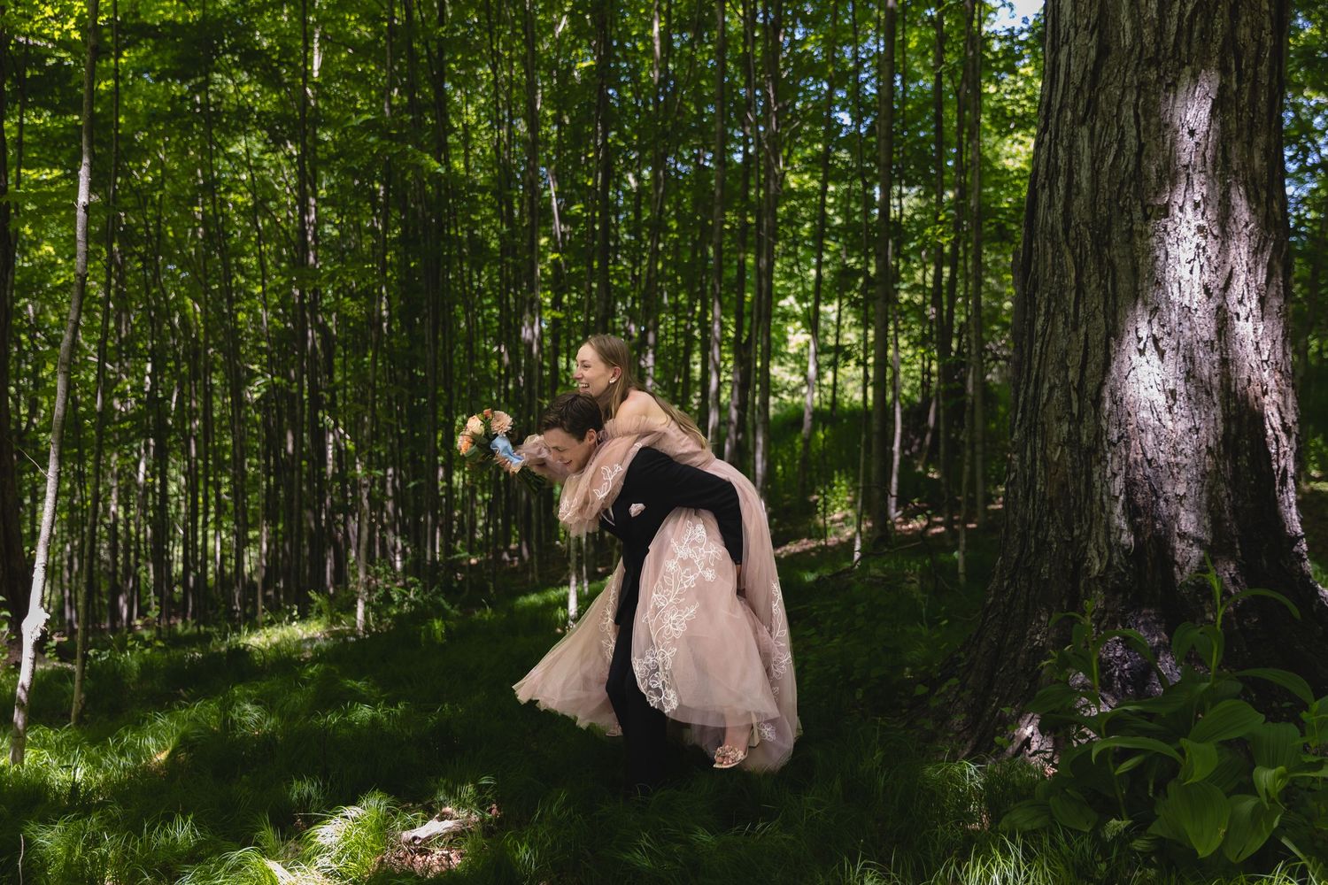 Groom dips bride in a lush green forest during a romantic outdoor wedding photo session.