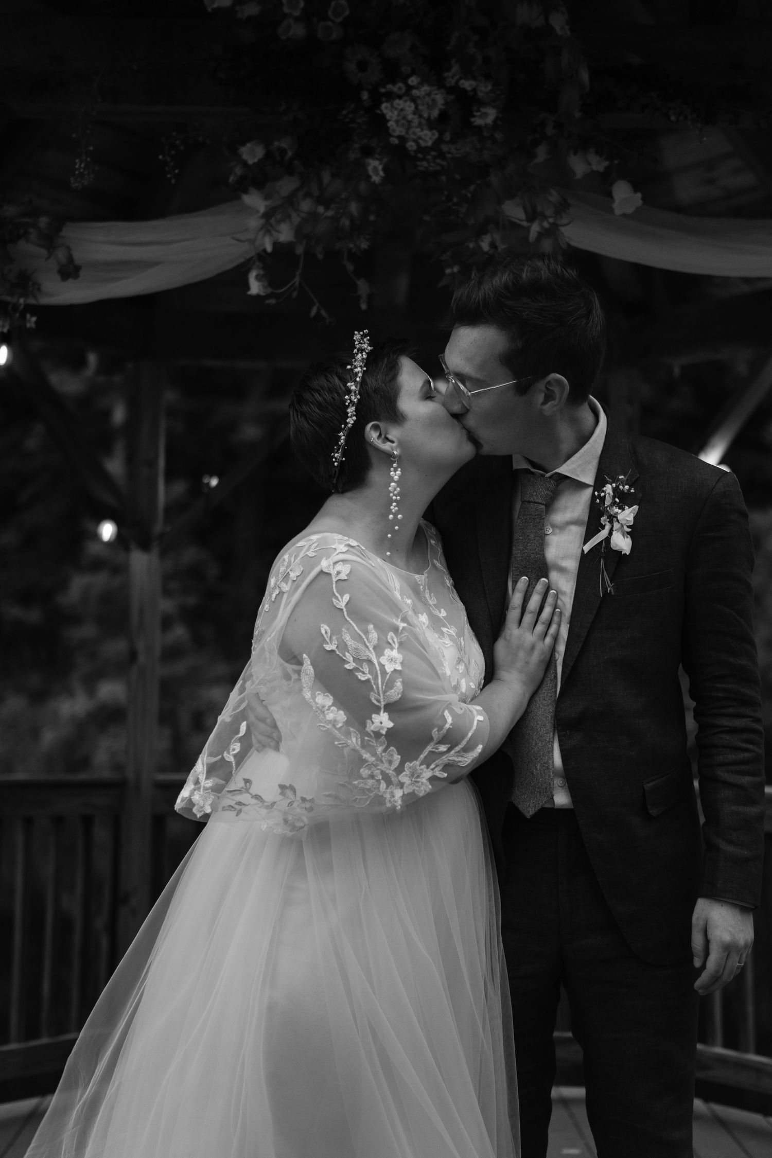 A romantic black and white wedding photo captured under twinkling lights.
