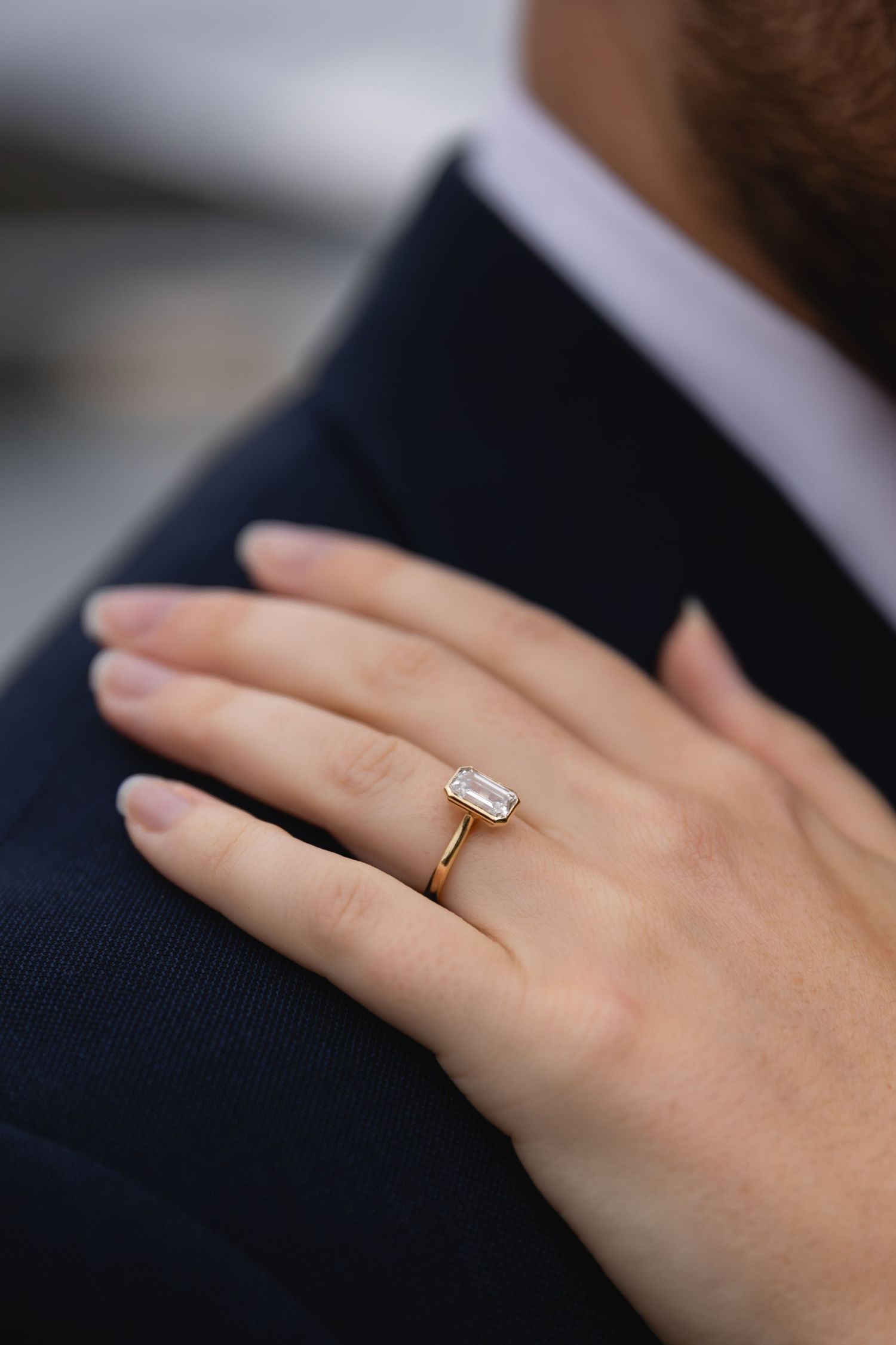 Close-up of an elegant engagement ring with a rectangular diamond on a delicate gold band.