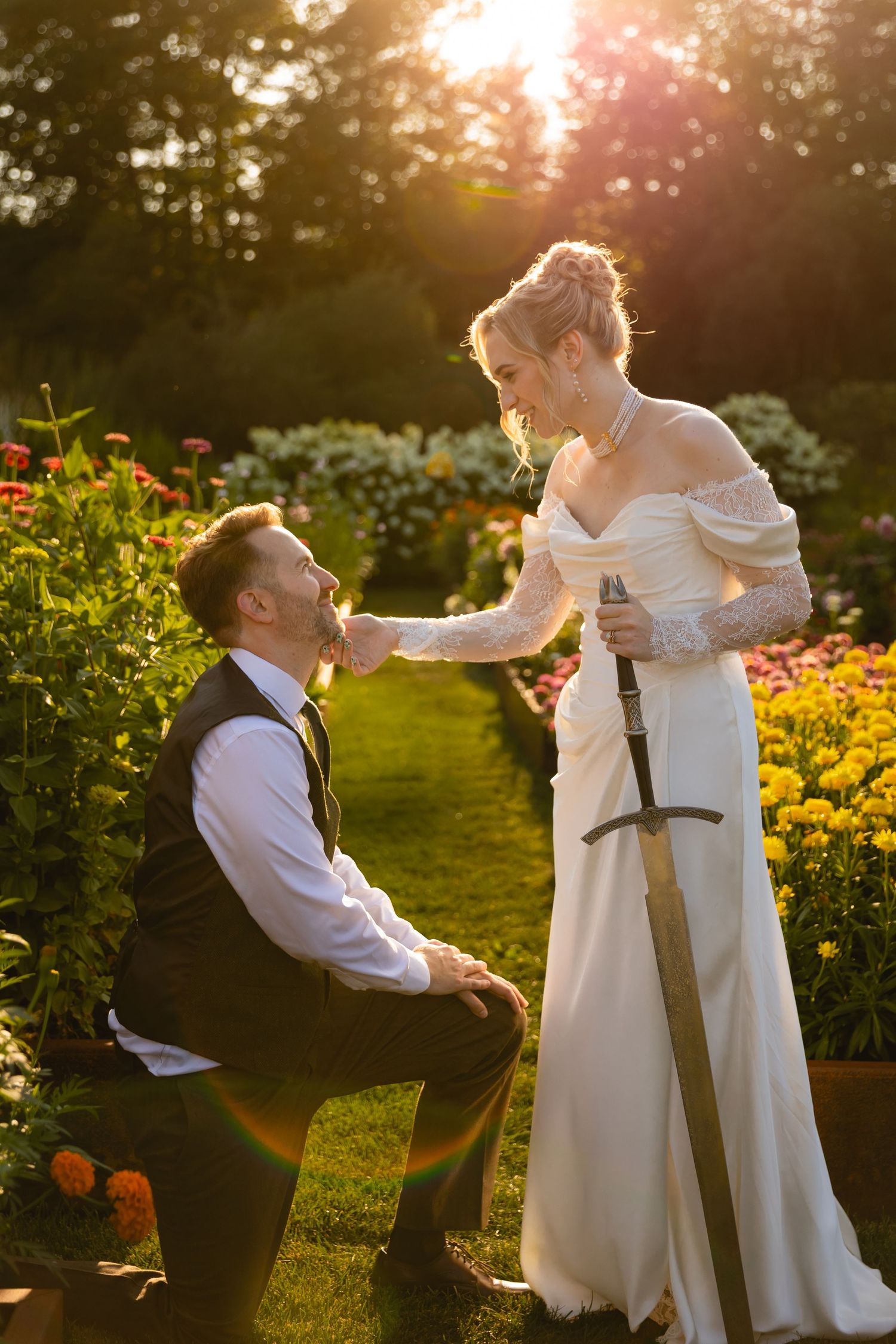 Romantic wedding couple embraces in a garden at sunset with golden marigolds blooming in the background.