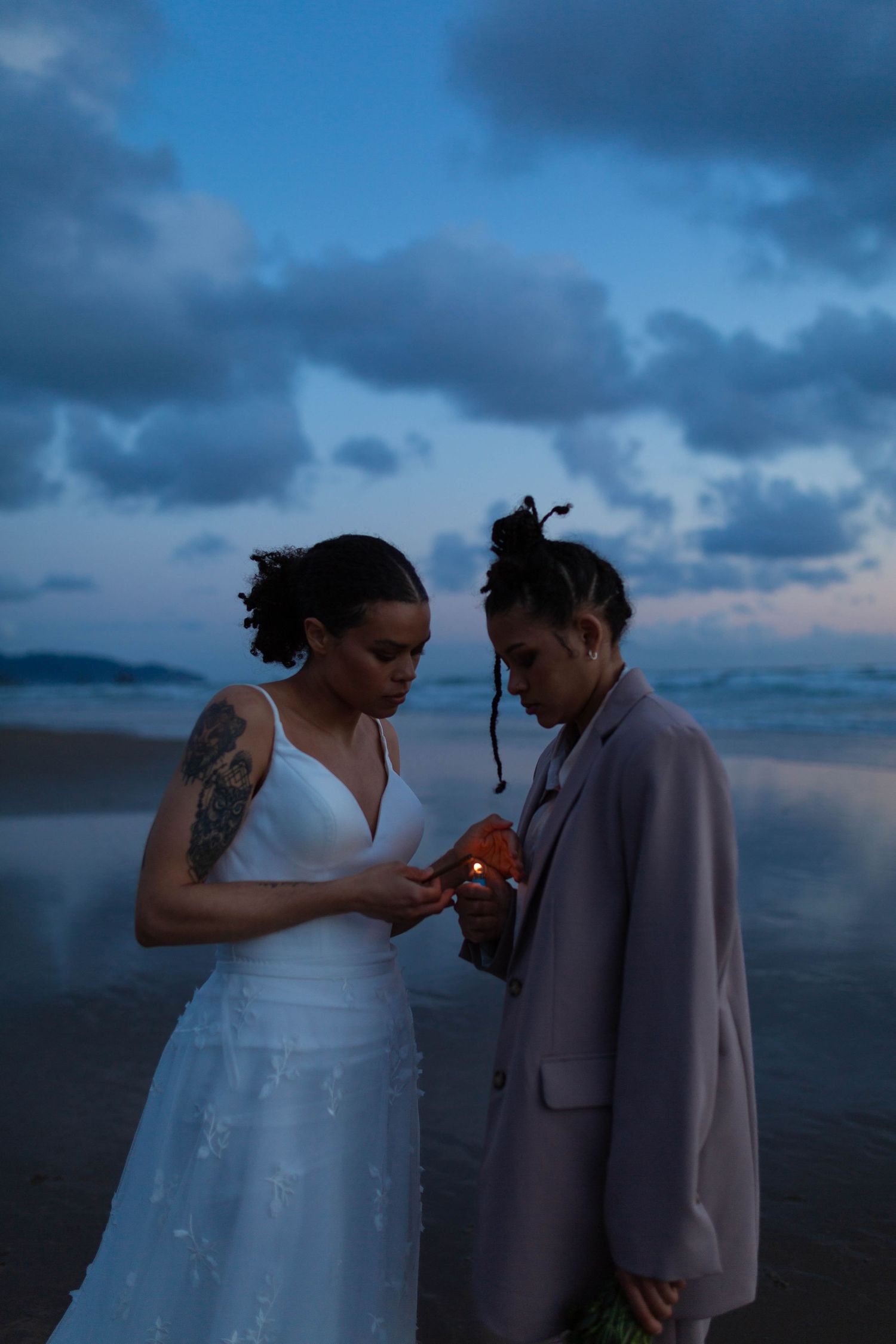 A romantic sunset beach wedding scene with two people looking at a ring in moody blue lighting.
