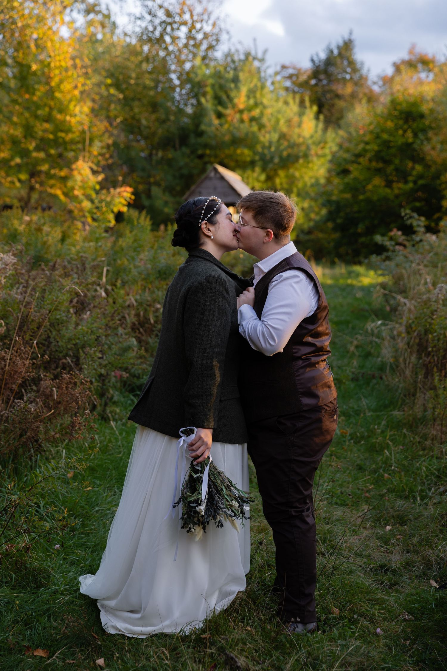 A tender moment between newlyweds sharing a kiss on an autumn path.