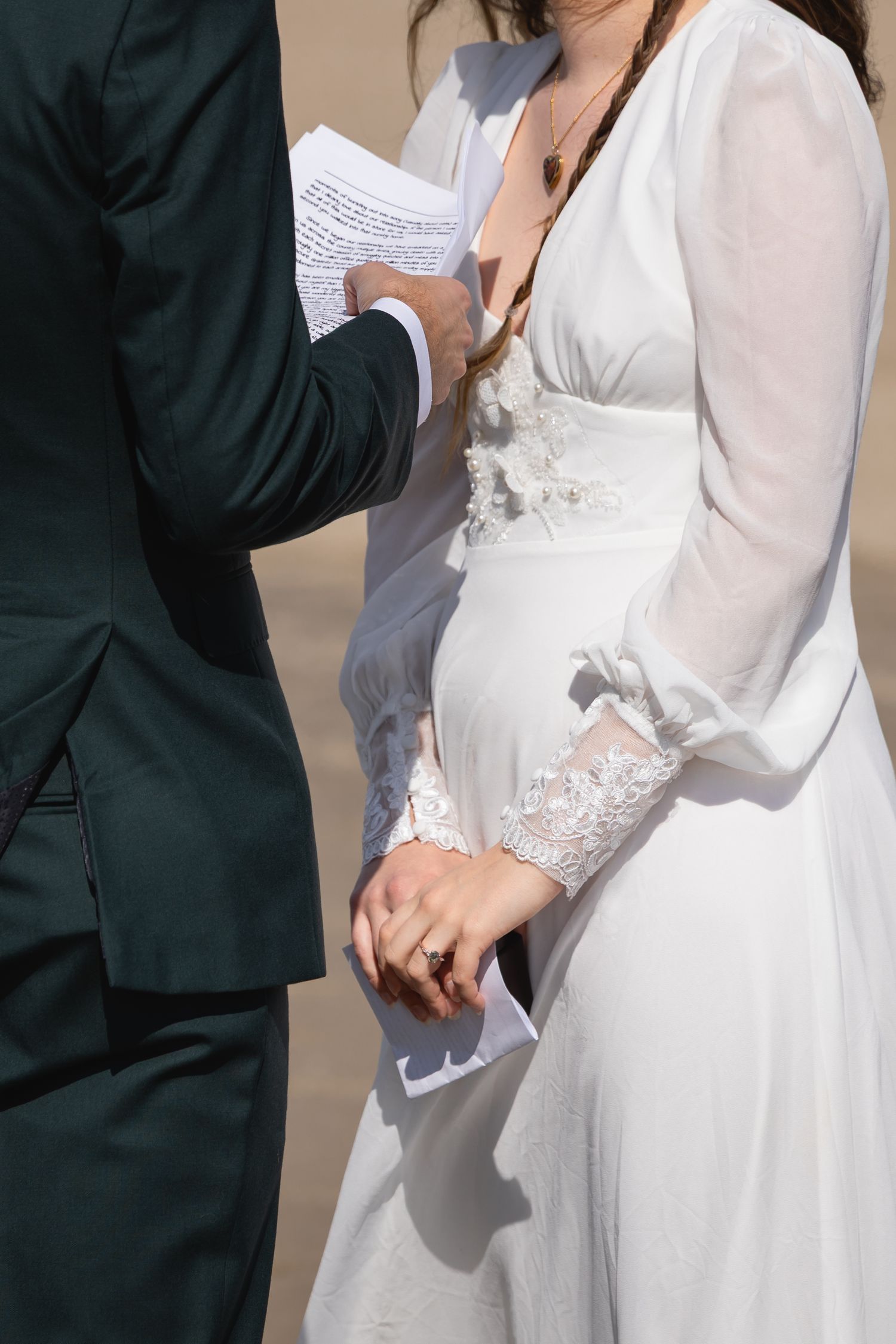 A bride and groom stand together during their wedding ceremony, with the bride wearing a flowing white dress.