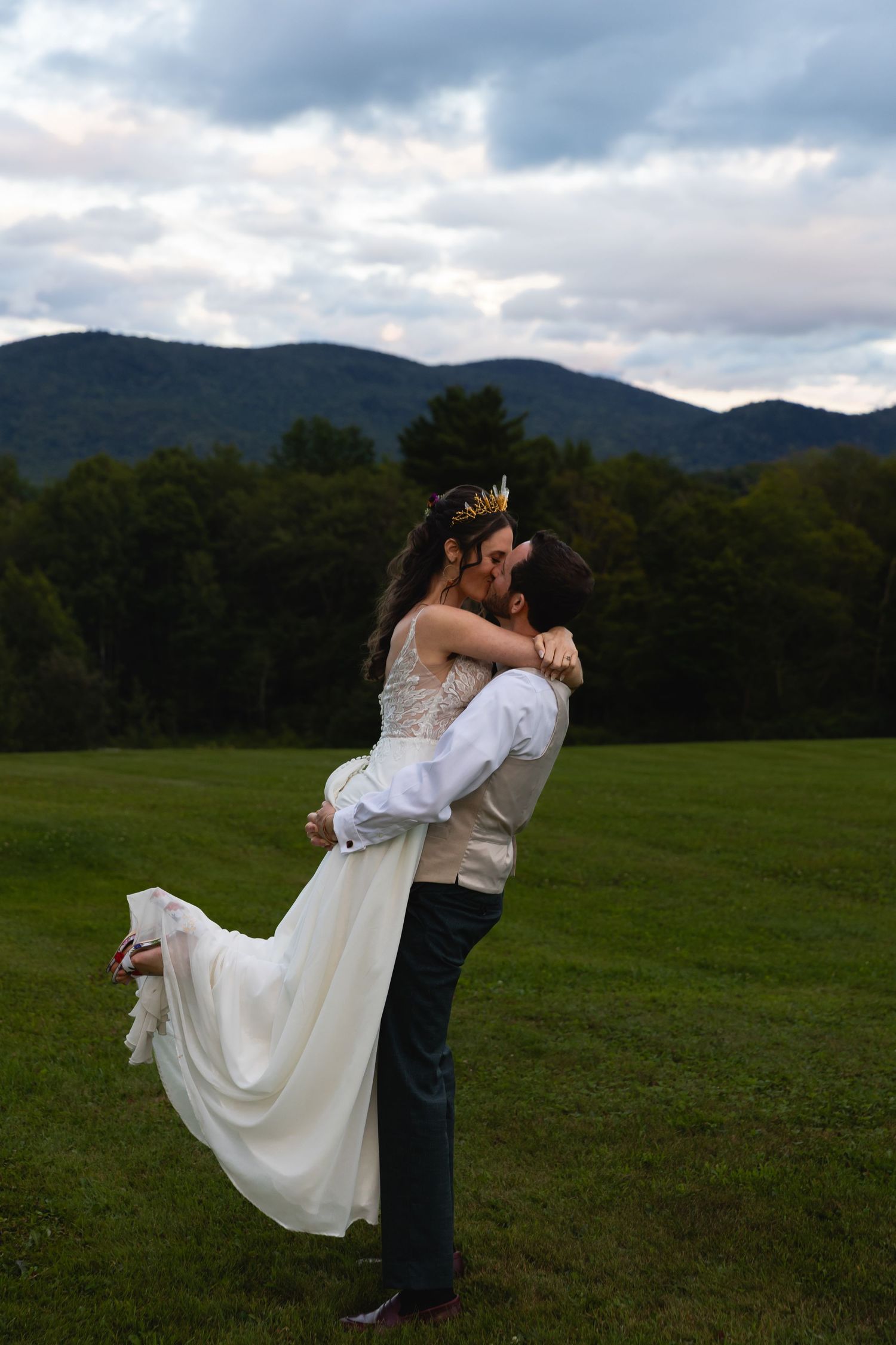 Romantic outdoor wedding portrait with mountain landscape backdrop.