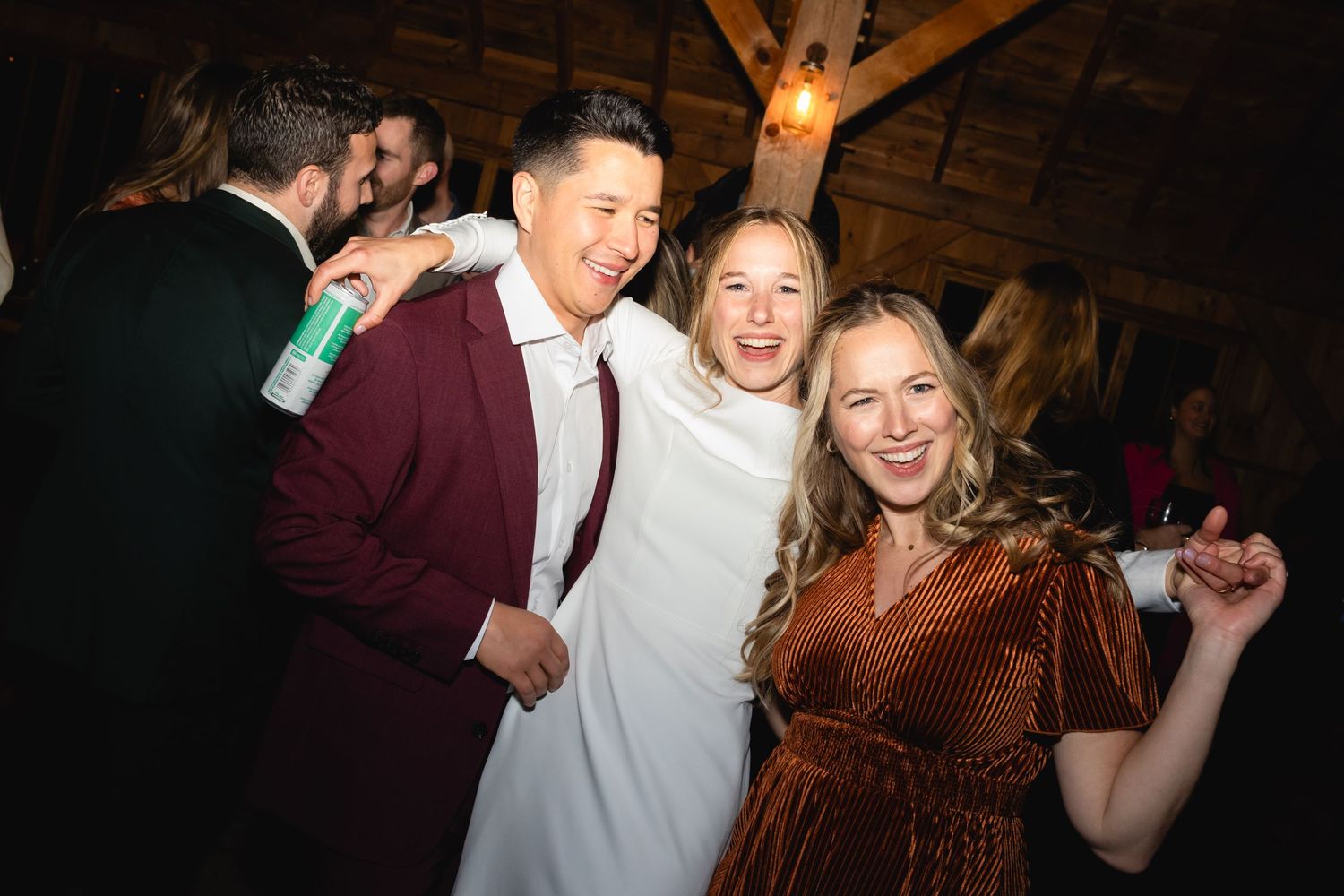 A group of friends enjoying themselves at a party with one wearing a burgundy sweater and another in a copper dress.