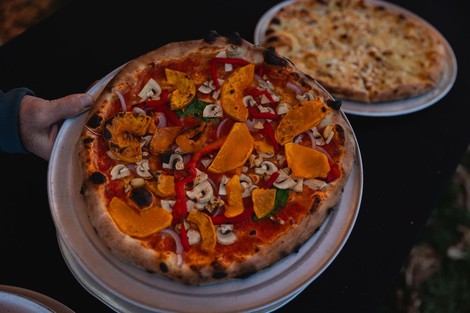 Freshly baked pizza topped with colorful vegetables and melted cheese on a white plate.