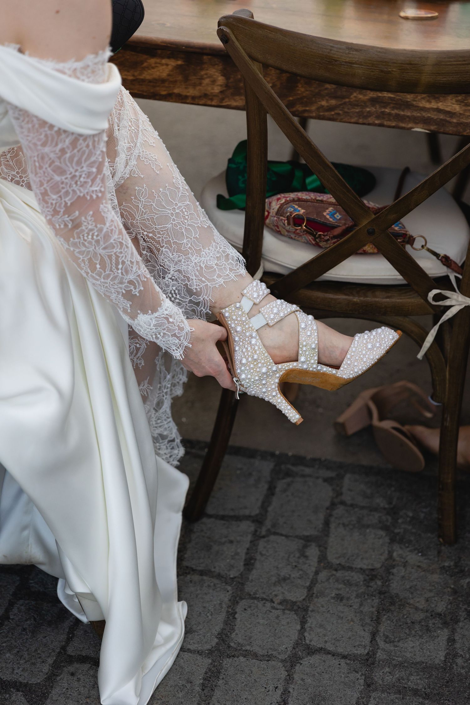 Close-up view of delicate lace sleeves on a white wedding dress as someone adjusts the cuff details.