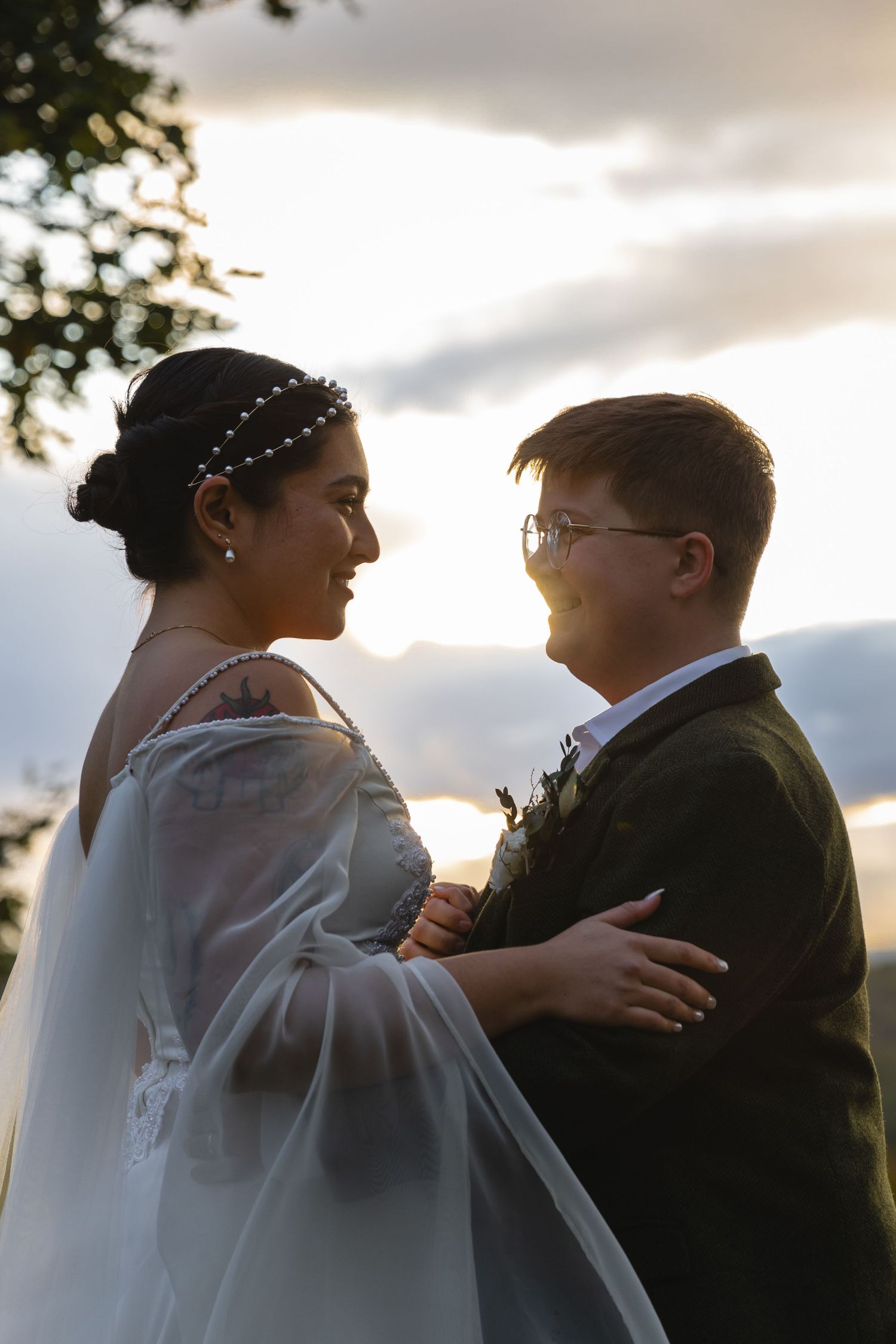 A romantic wedding portrait at sunset showing a couple embracing with mountains in the background.