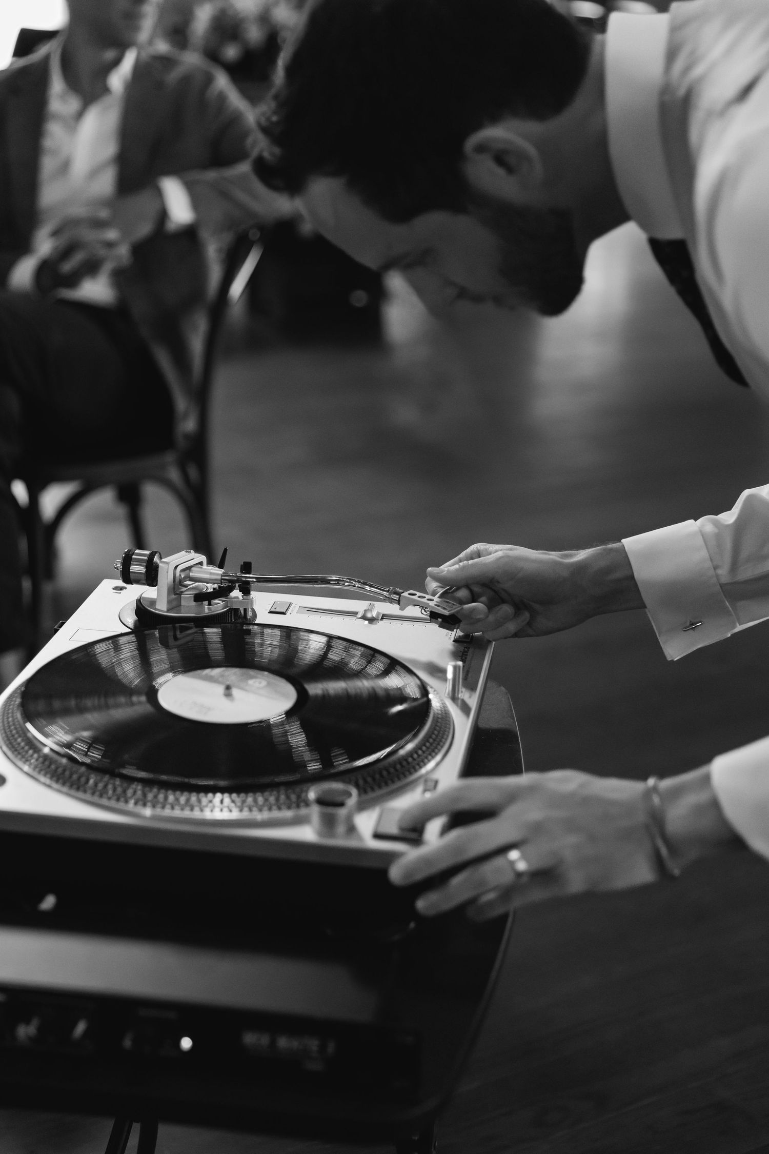Black and white photo of someone adjusting a vintage turntable.