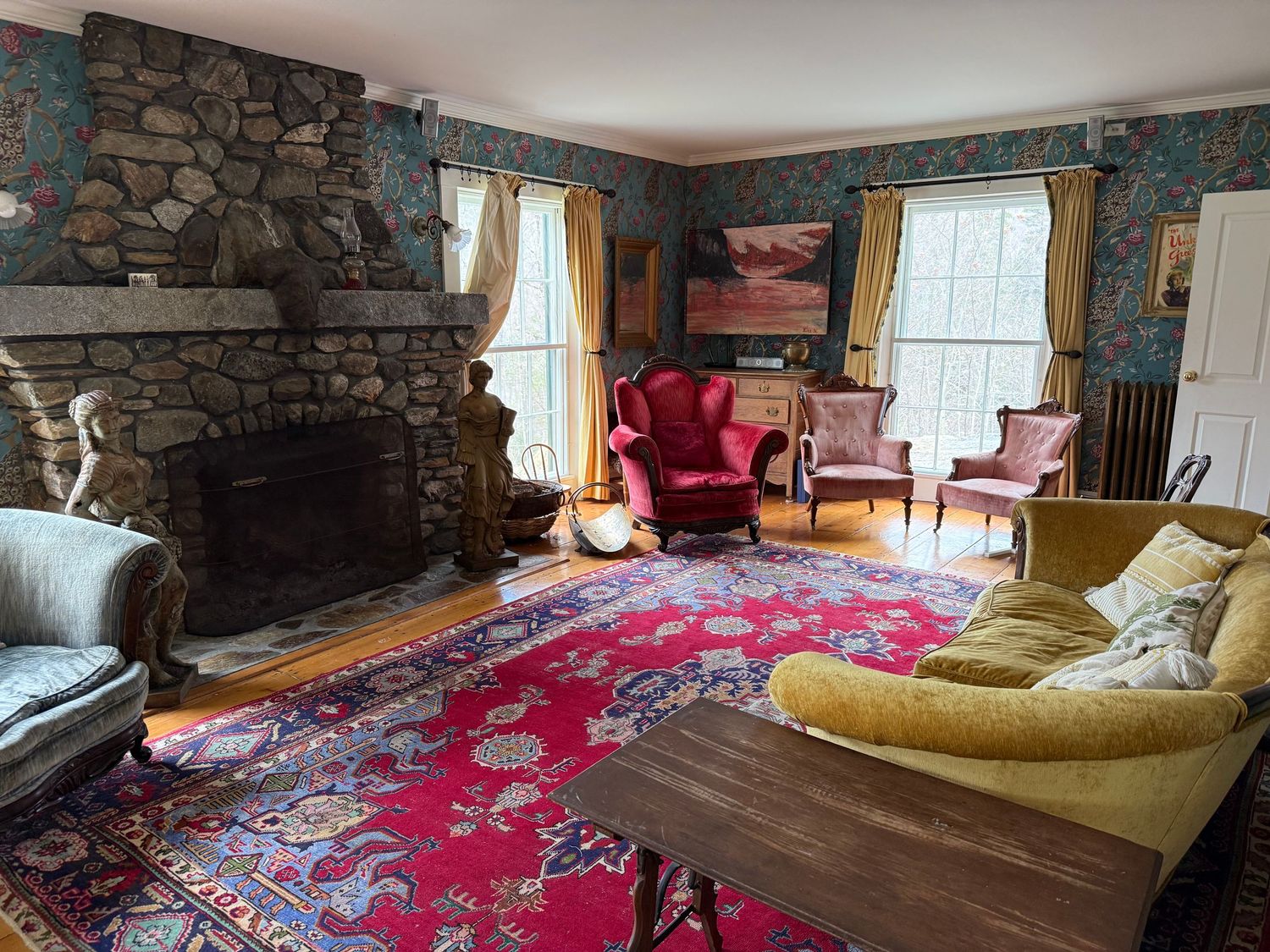 Rustic living room interior with stone fireplace, red area rug, and yellow lounge furniture in a cozy cabin setting.